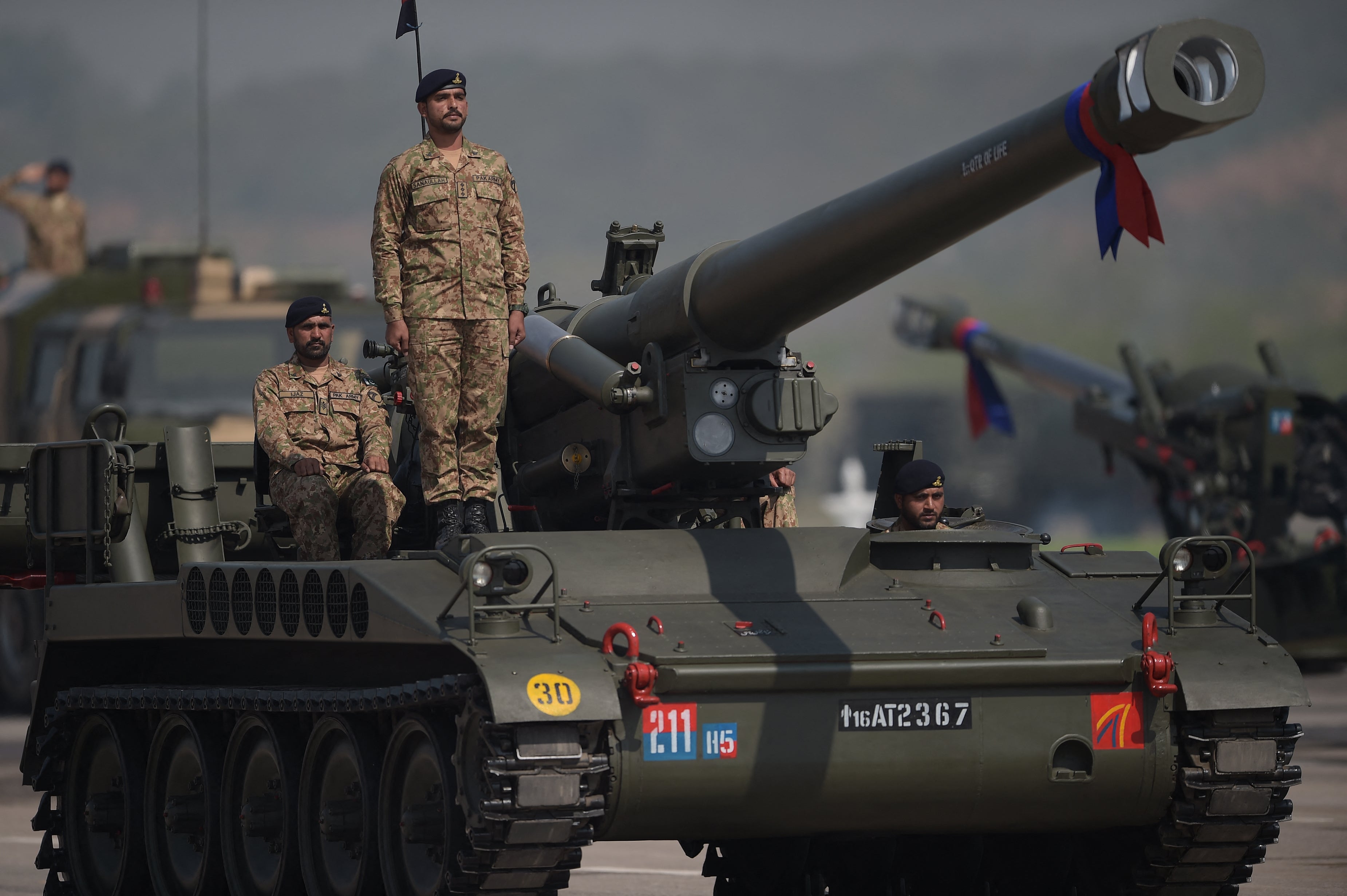 Pakistani military personnel travel on a tank during a Pakistan Day military parade
