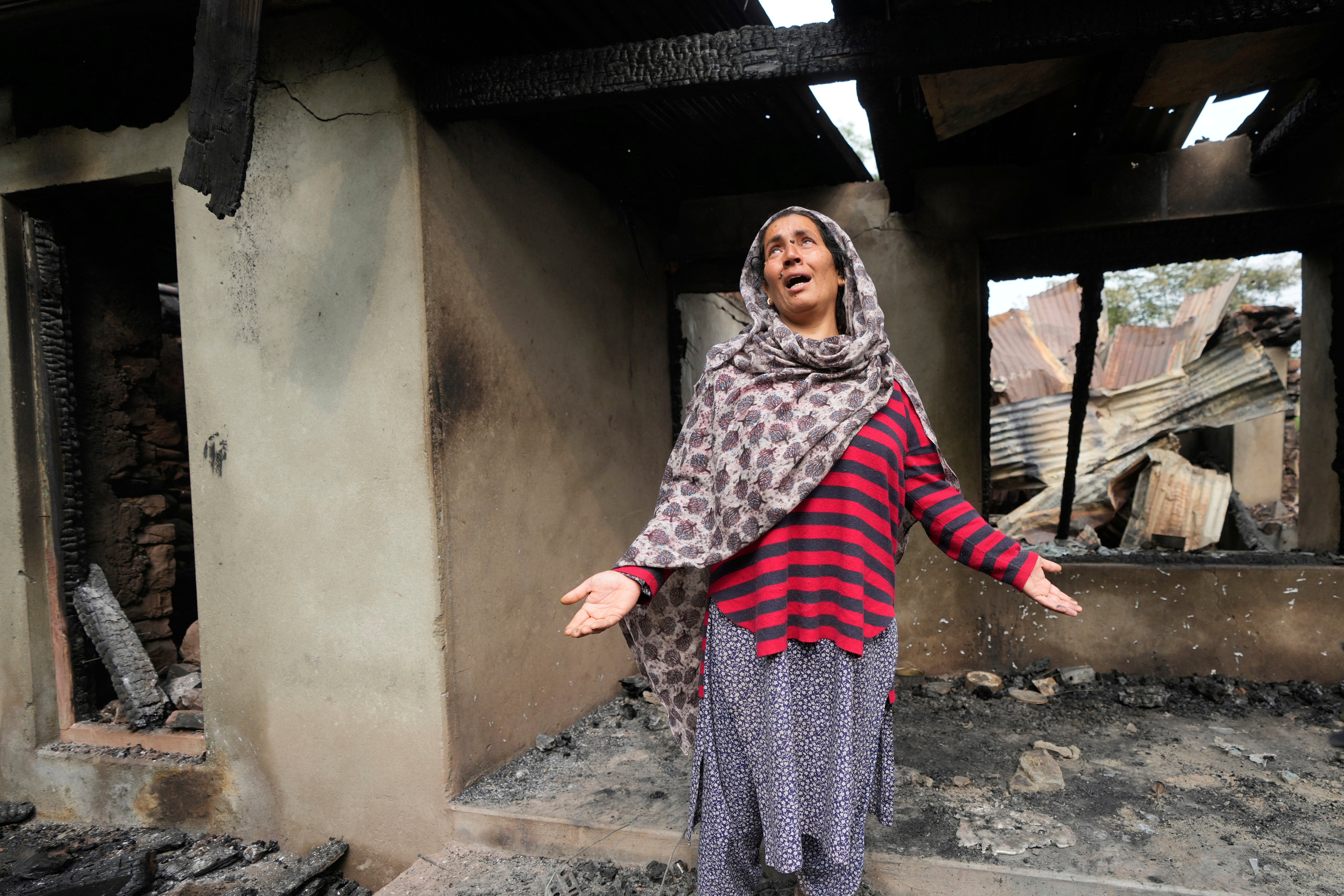 A woman wails as she stands outside her house destroyed by Pakistani artillery shelling