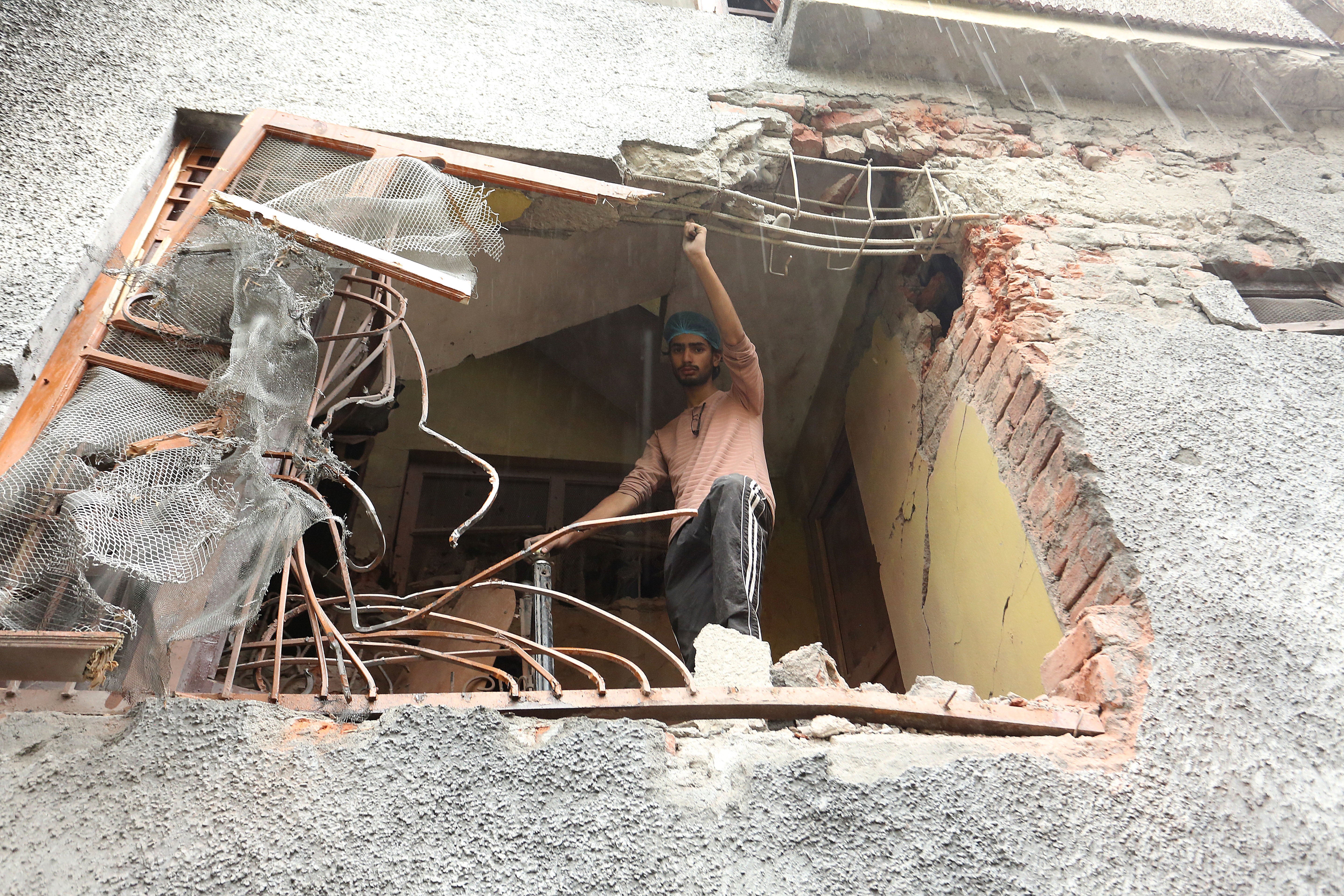 A man stands in a damaged house in Poonch