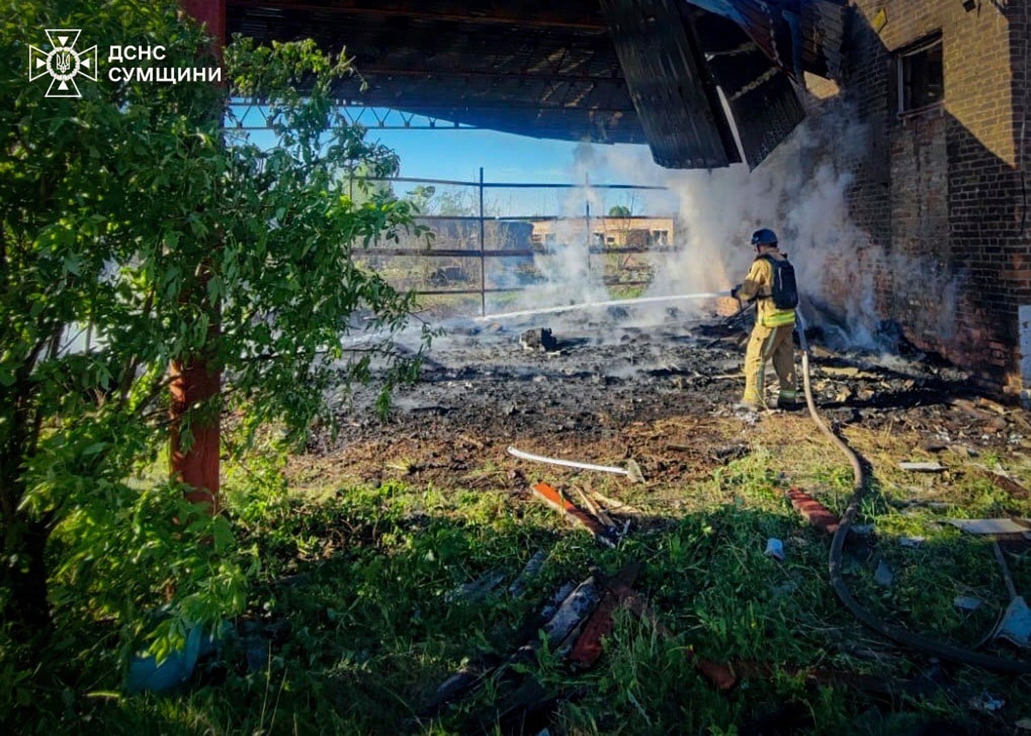 A rescue worker puts out a fire of a building which was heavily damaged by a Russian strike in Sumy region, Ukraine