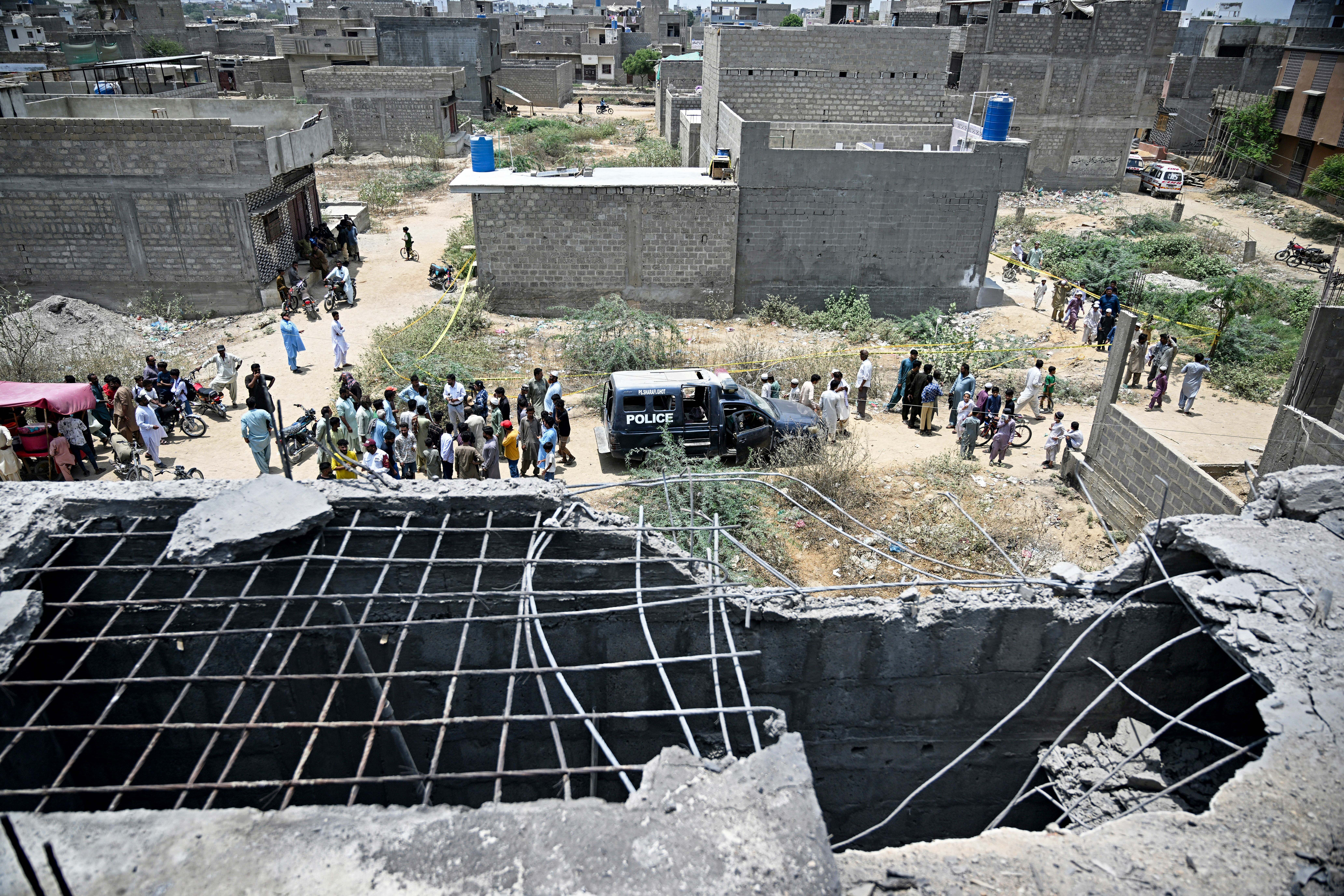 Residents gather as police personnel inspect the site where a drone was reportedly shot down in Karachi on 8 May 2025