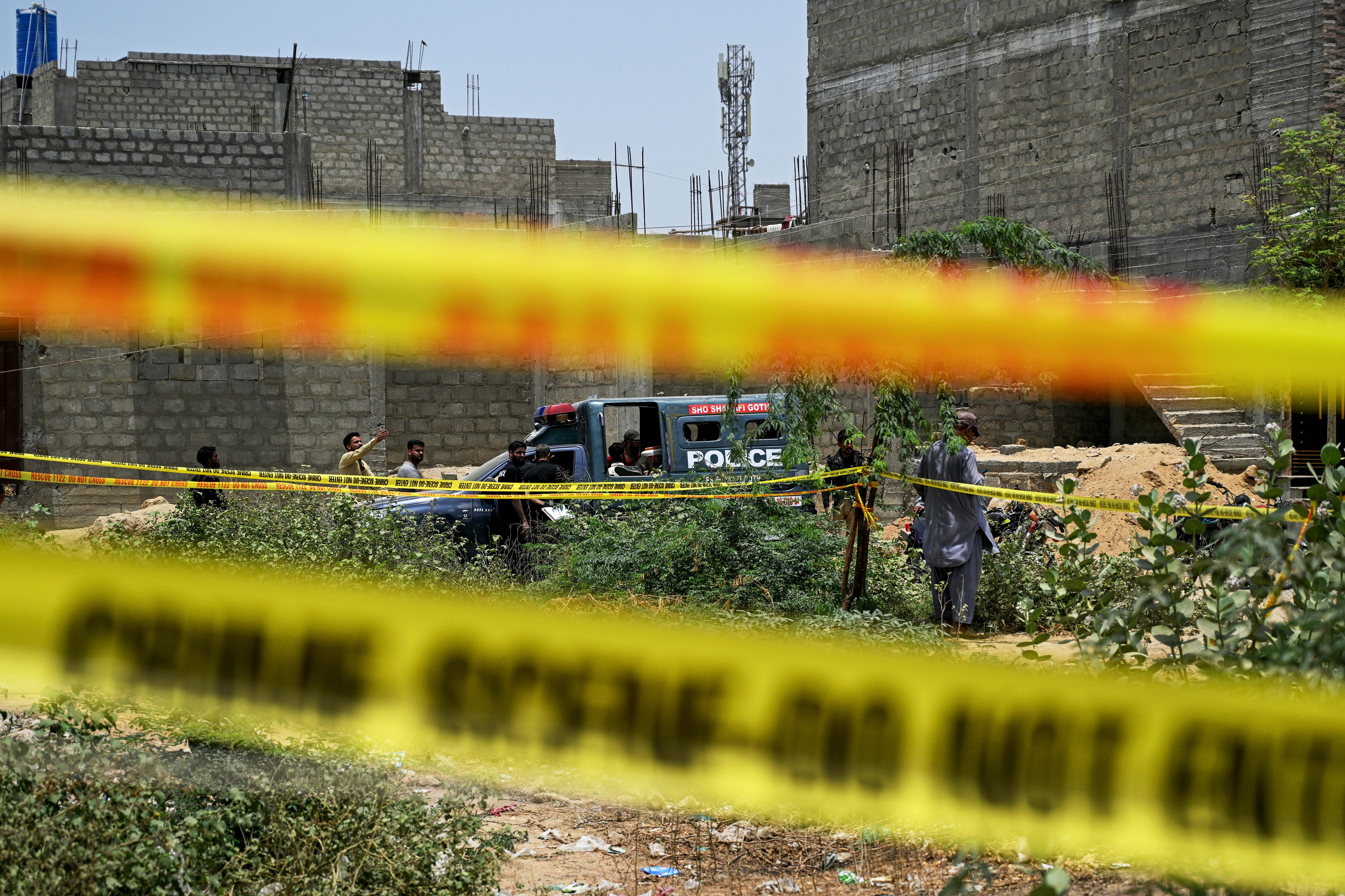 Residents gather as police personnel inspect a site cordoned off with barricade tapes after an alleged drone was shot down in Karachi on 8 May 2025