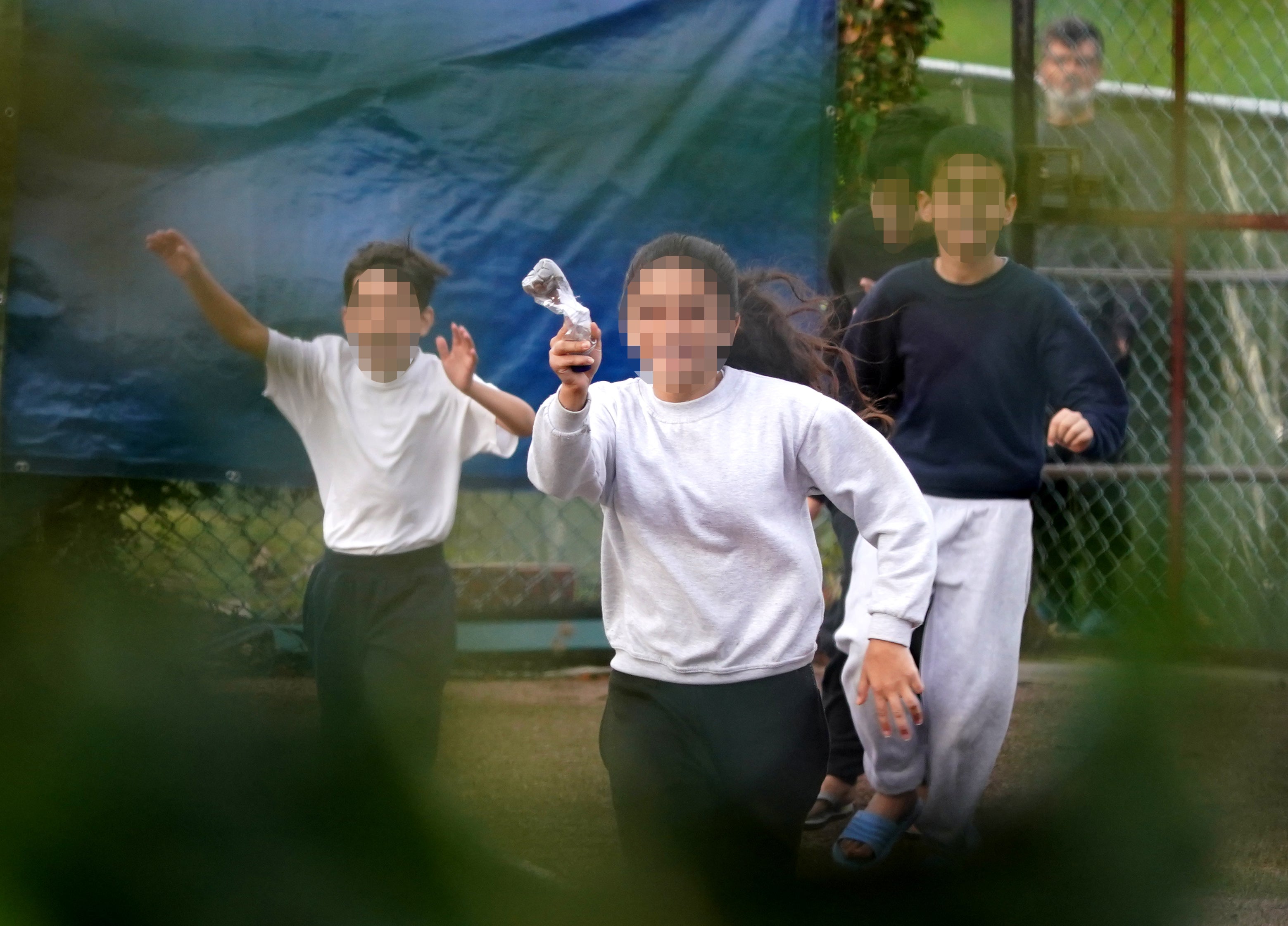A young girl runs towards the fence carrying a message in a bottle describing conditions inside the Manston immigration short-term holding facility