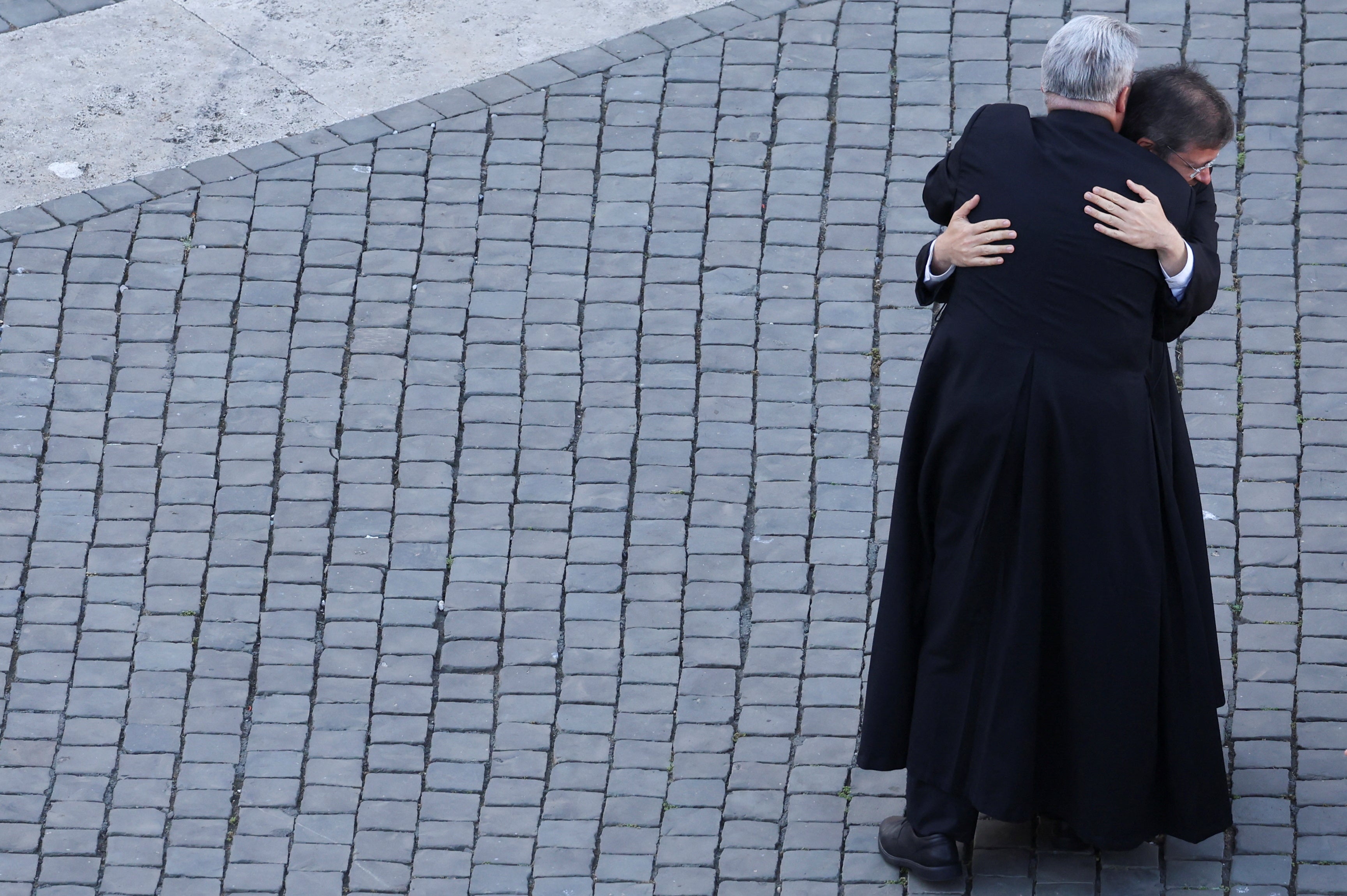 Priests embrace after the white smoke is seen
