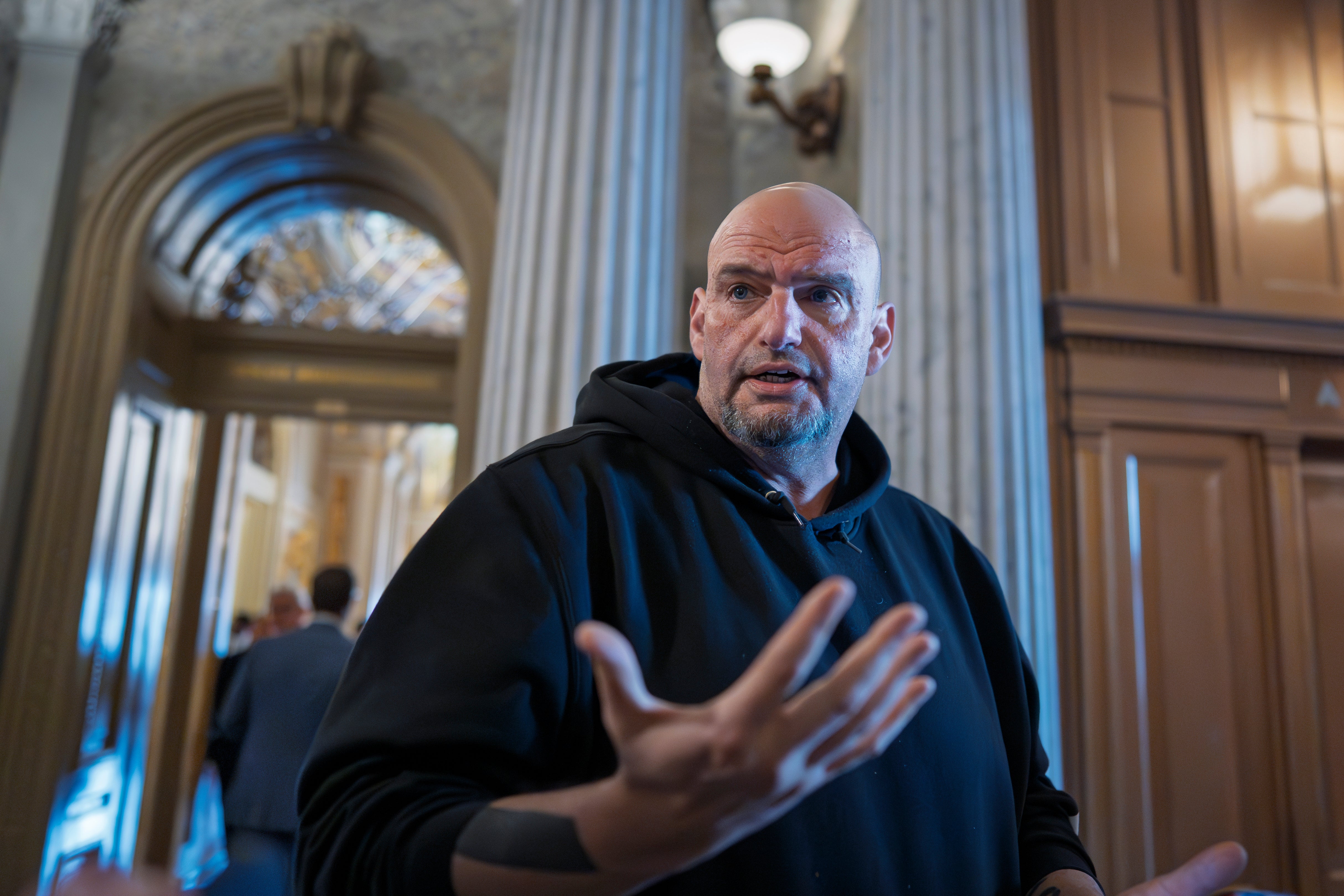 John Fetterman talks to reporters outside the chamber during a vote at the Capitol in Washington, March 13, 2025. He has rejected allegations of reckless behavior amid reports about his mental health