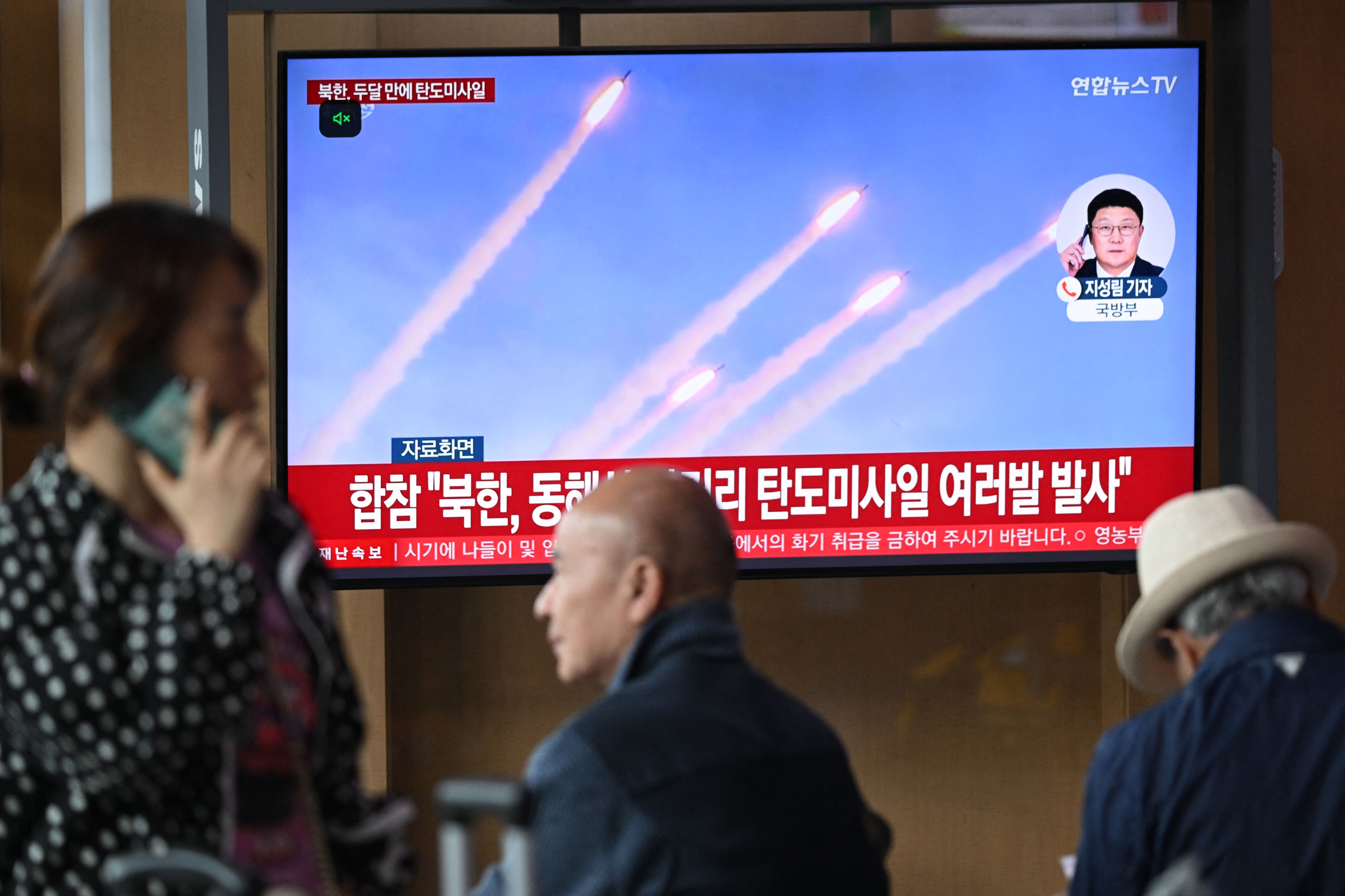 People watch a television screen showing a news broadcast with file footage of a North Korean missile test, at a train station in Seoul