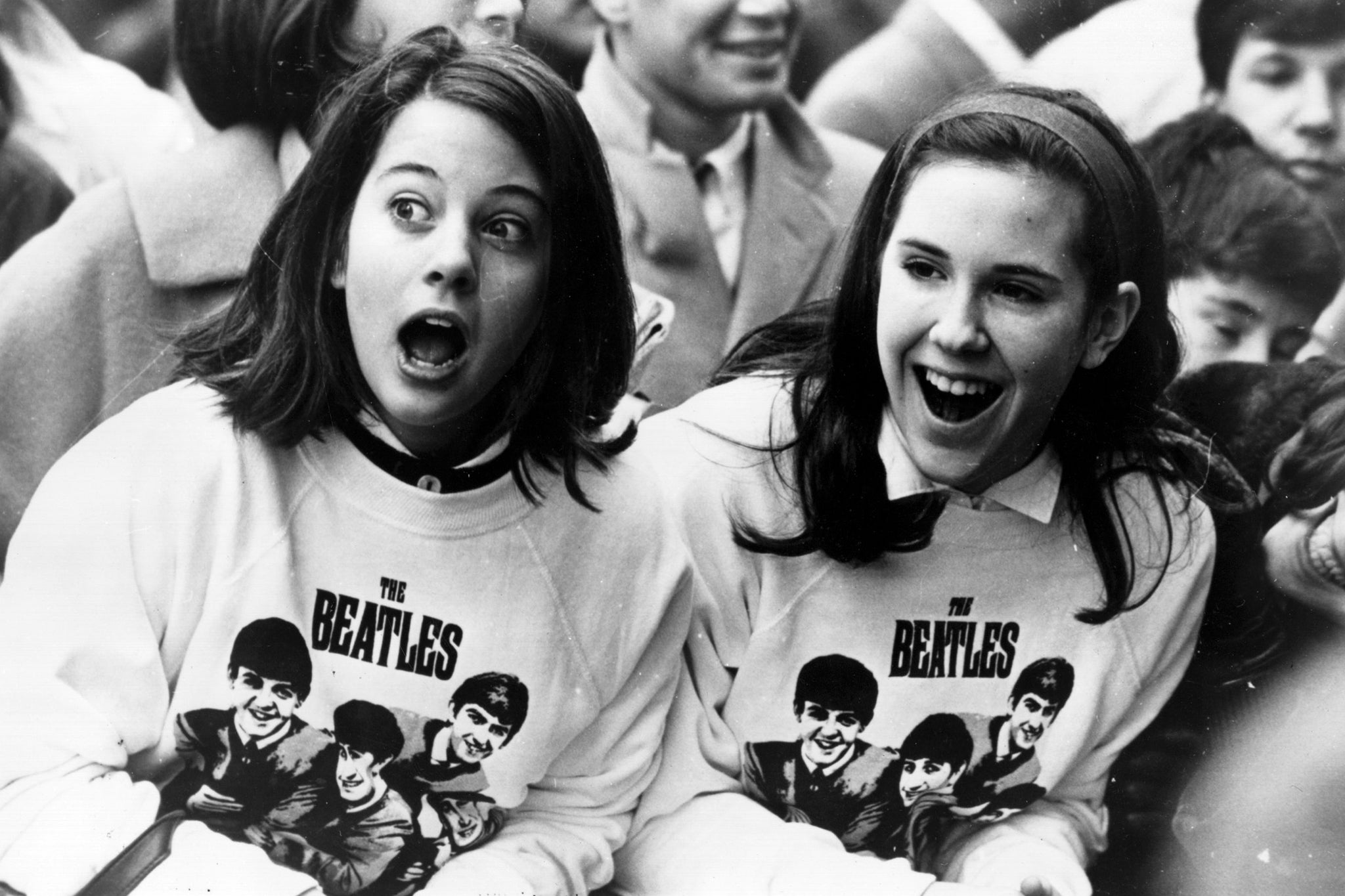  two girls in Beatles sweatshirts wait for the band's arrival in New York in 1964
