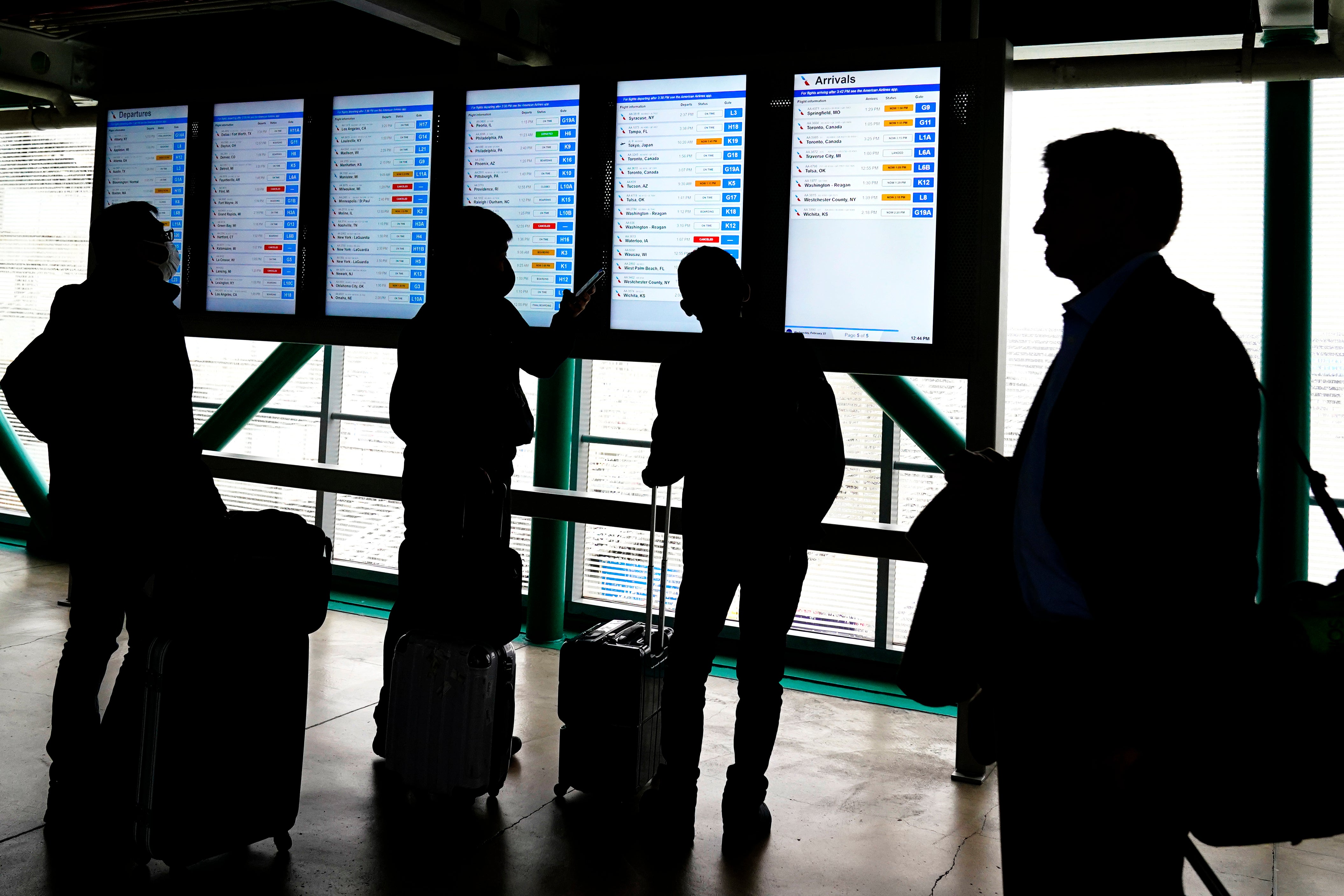 Travelers check American Airlines flight information screens for their flight status at O'Hare International Airport in Chicago, Wednesday, Feb. 22, 2023