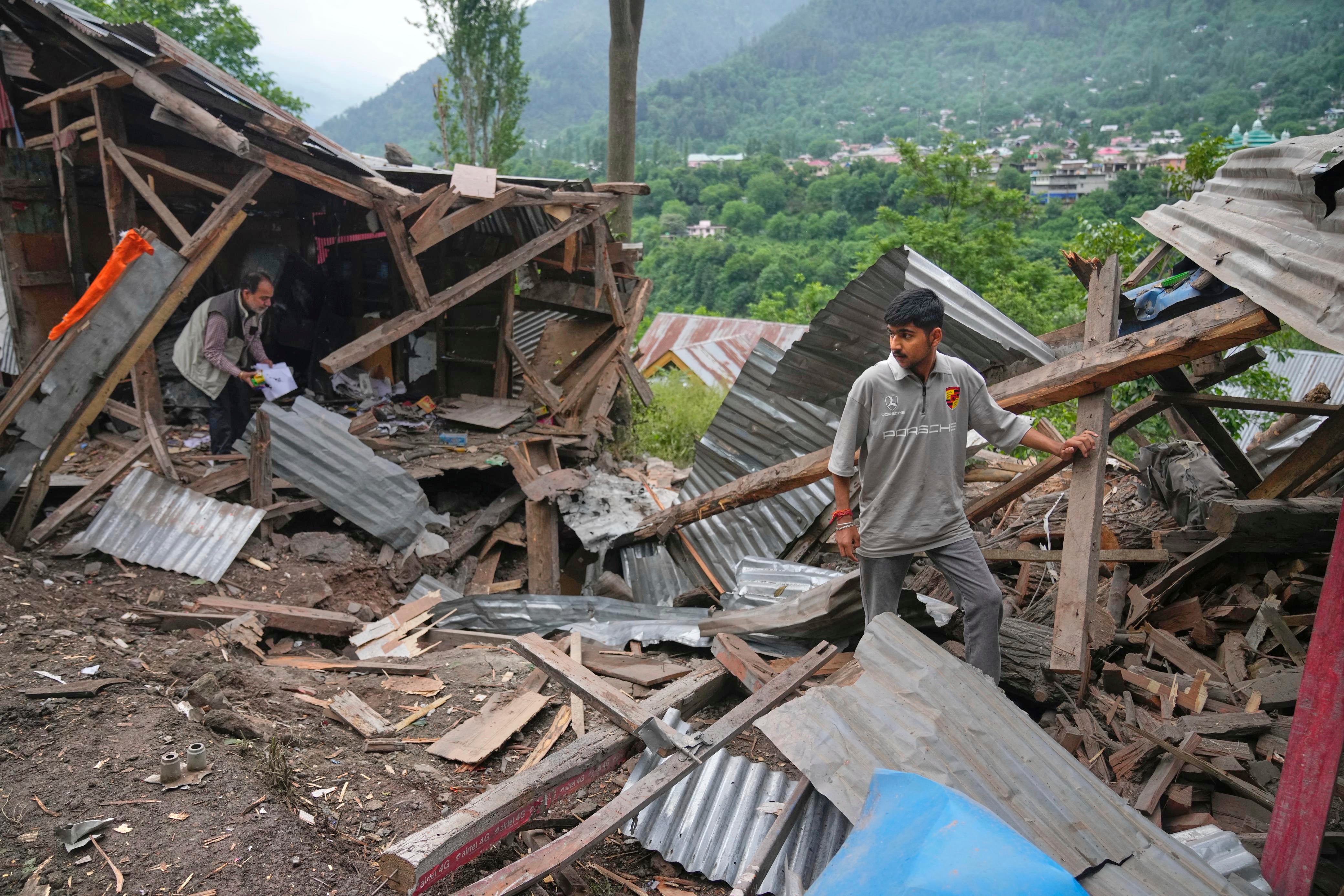 People inspect their damaged shops following overnight shelling from Pakistan