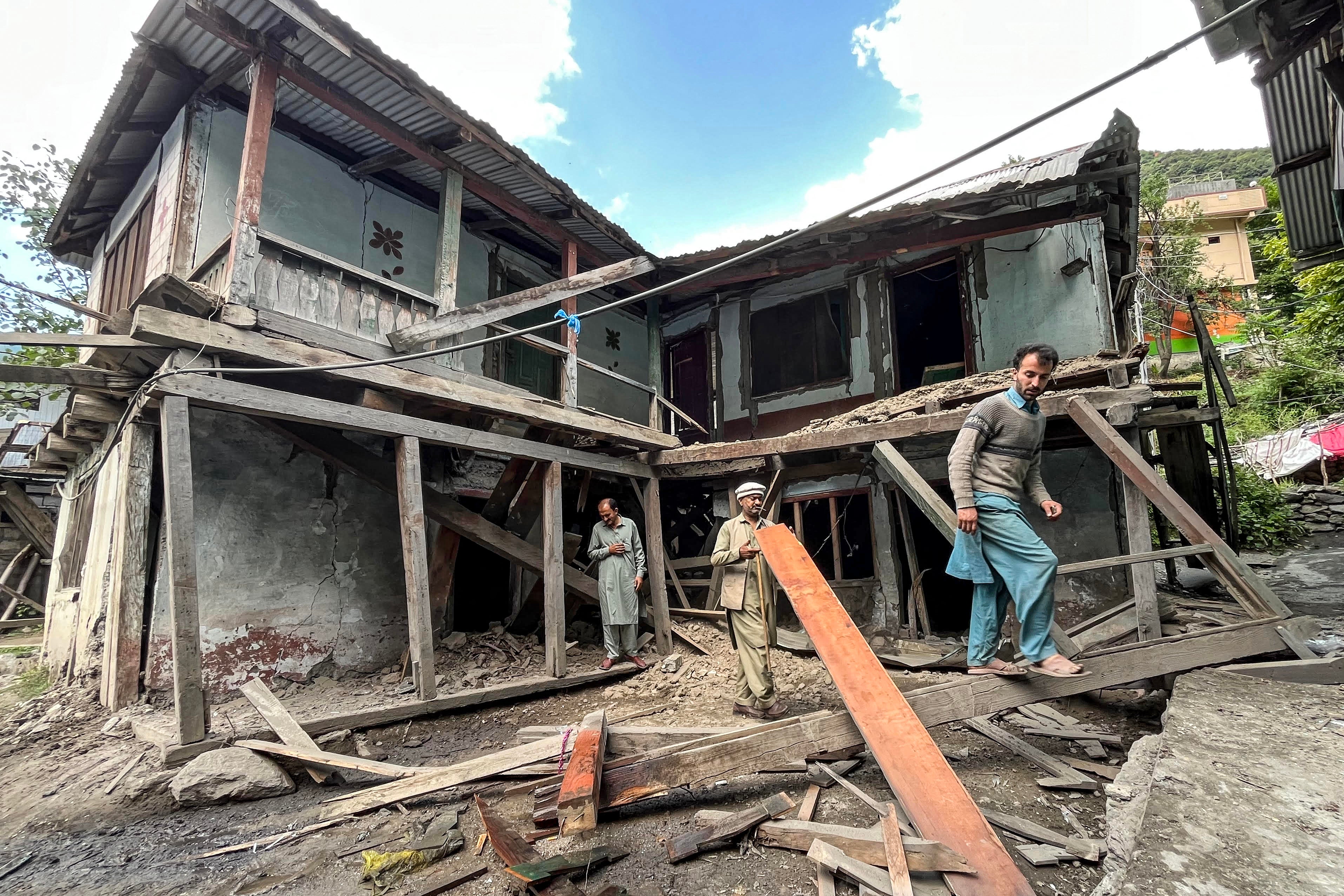 People remove debris from their houses damaged by Indian shelling in Jura sector of Neelum Valley in Pakistan-administered Kashmir on 10 May 2025