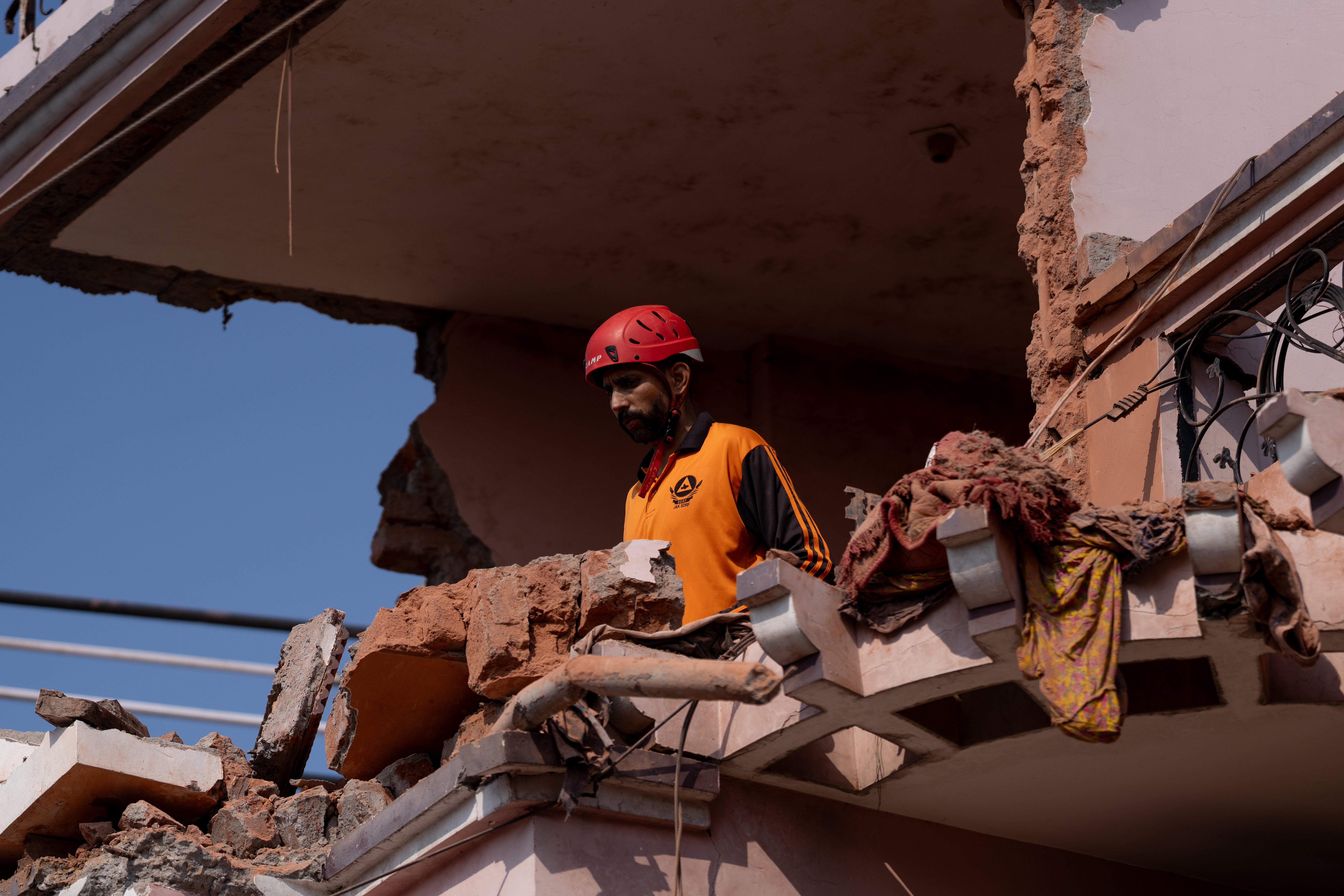 A rescue worker helps remove debris of a residential building that was damaged in an aerial attack from Pakistan in Jammu, India, before the ceasefire was announced
