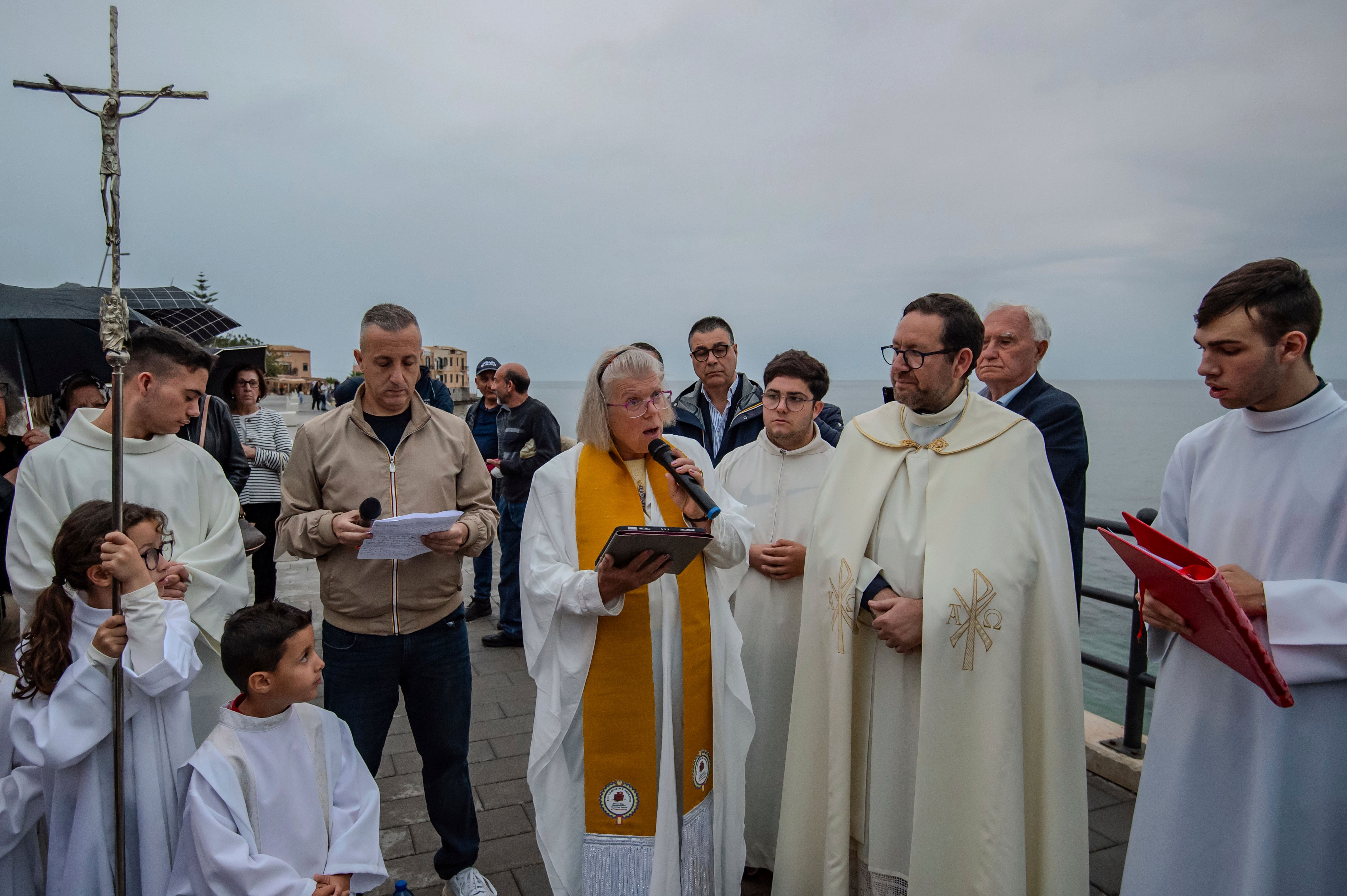 Deacon of the Church of England, Carrie Pemberton Ford, center, speaks, Sunday, May 4, 2025, after attending a Mass celebrated by Catholic priest, father Lorenzo Buscemi, second from right, in the Sicilian village of Porticello, southern Italy, for the victims of the British superyacht Bayesian which sank off Porticello, on Aug. 19, 2024. (AP Photo/Salvatore Cavalli)