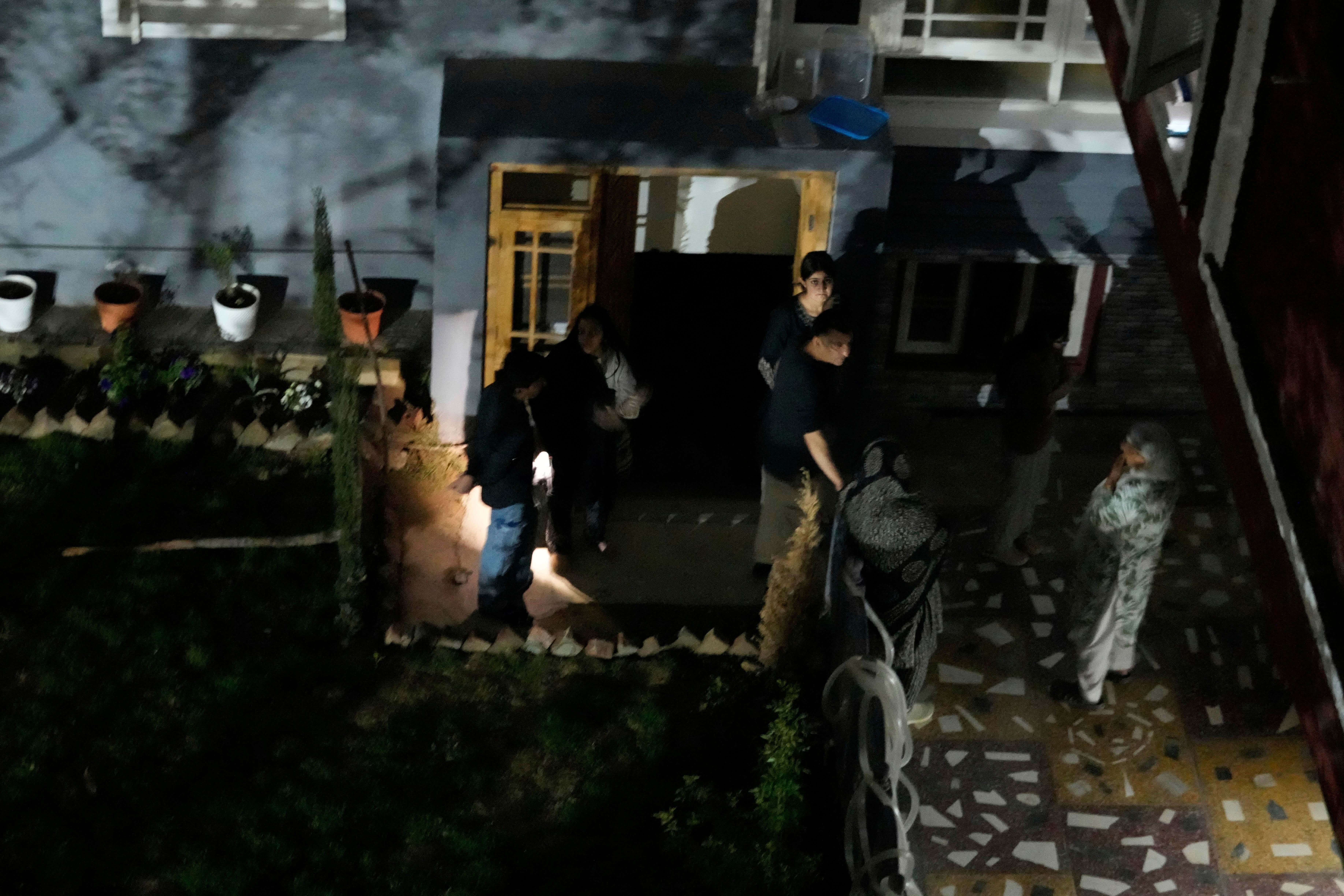 A Kashmiri family outside their home as projectiles fly over the sky in Indian controlled Kashmir on Saturday (Mukhtar Khan/AP)