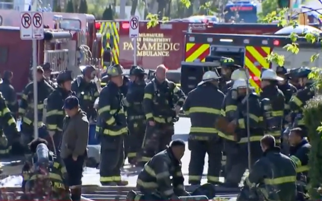 Firefighters gather outside a Milwaukee apartment building that was engulfed in flames Sunday, killing four people and injuring dozens more