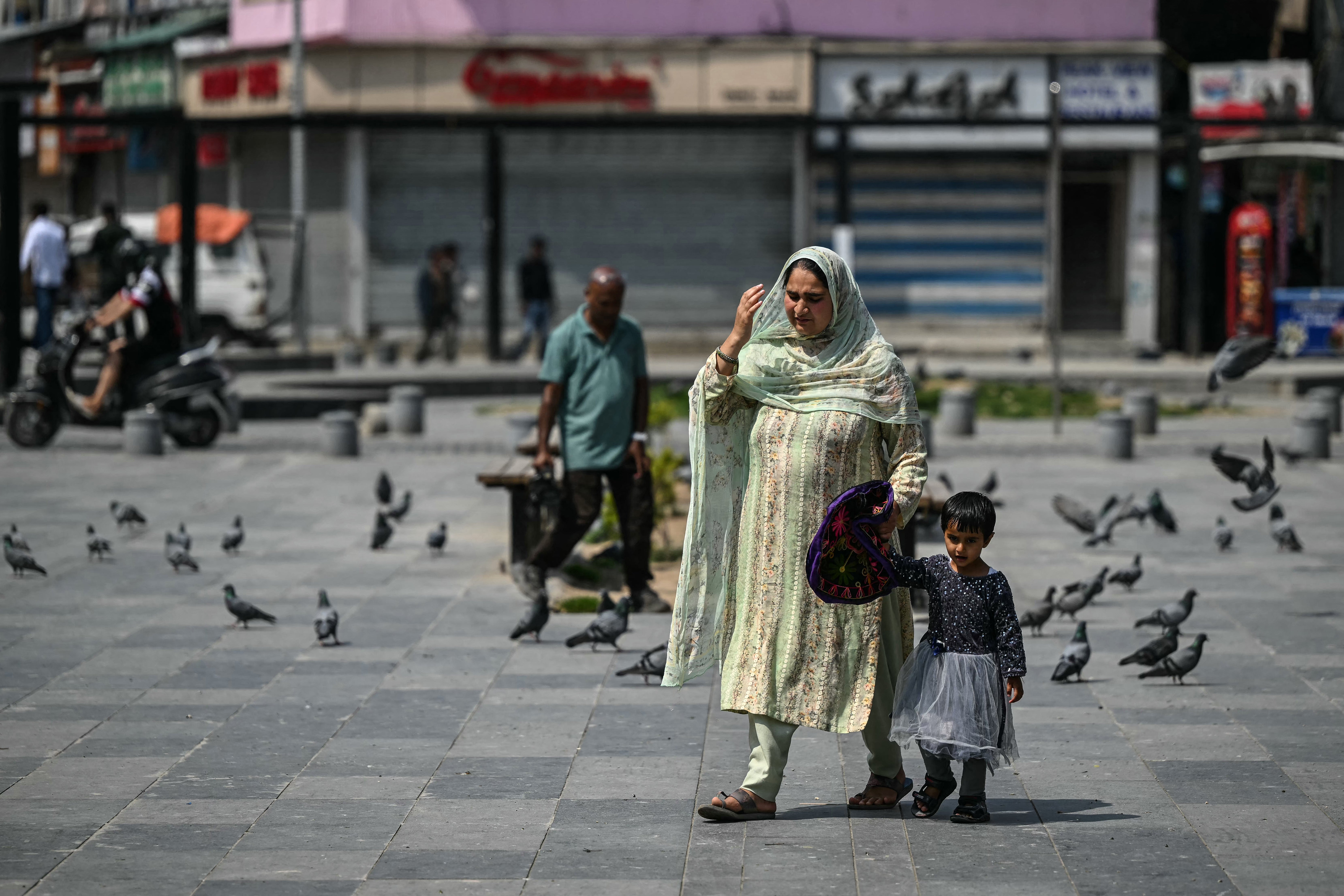 A woman and her child walk through a marketplace in Srinagar, Kashmir, on 11 May 2025
