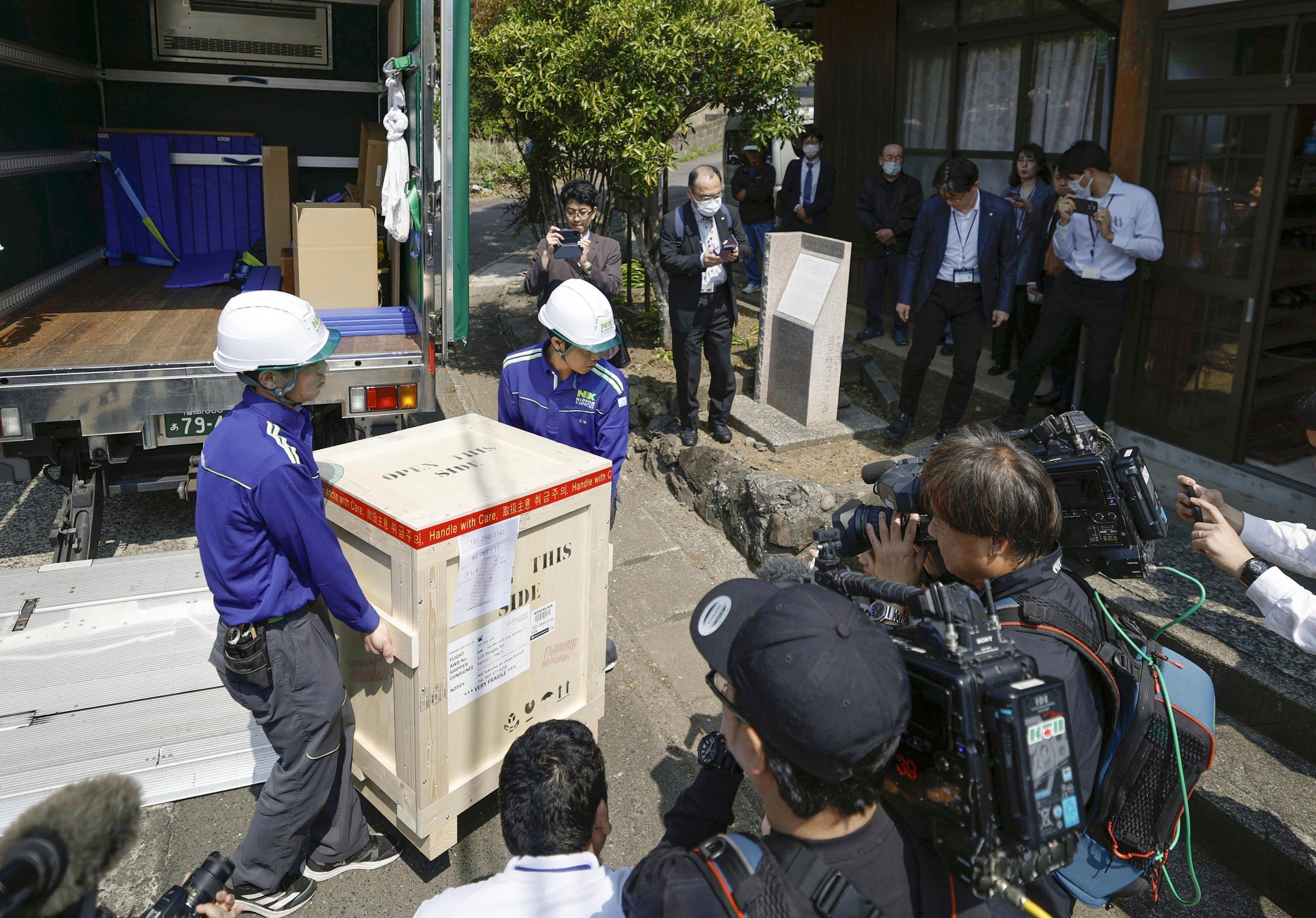 Delivery workers carry a 14th-century Buddhist statue of the Avalokitesvara Bodhisattva, stolen in October 2012 and taken to South Korea, into Kannon Temple upon its return, on Tsushima Island, southwestern Japan, Monday, May 12, 2025. (Haruna Furuhashi/Kyodo News via AP)