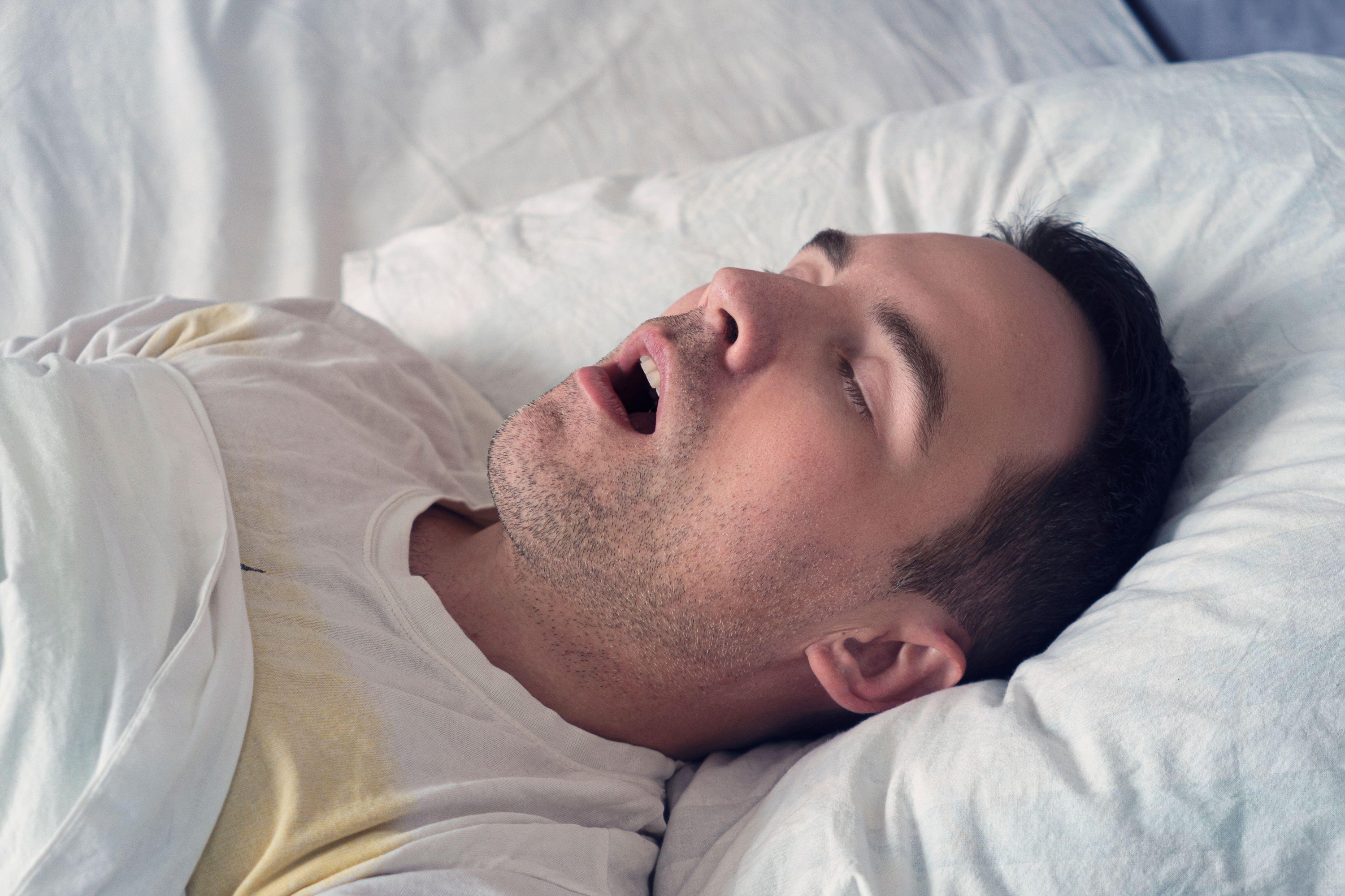 A young man snoring while sleeping on his back