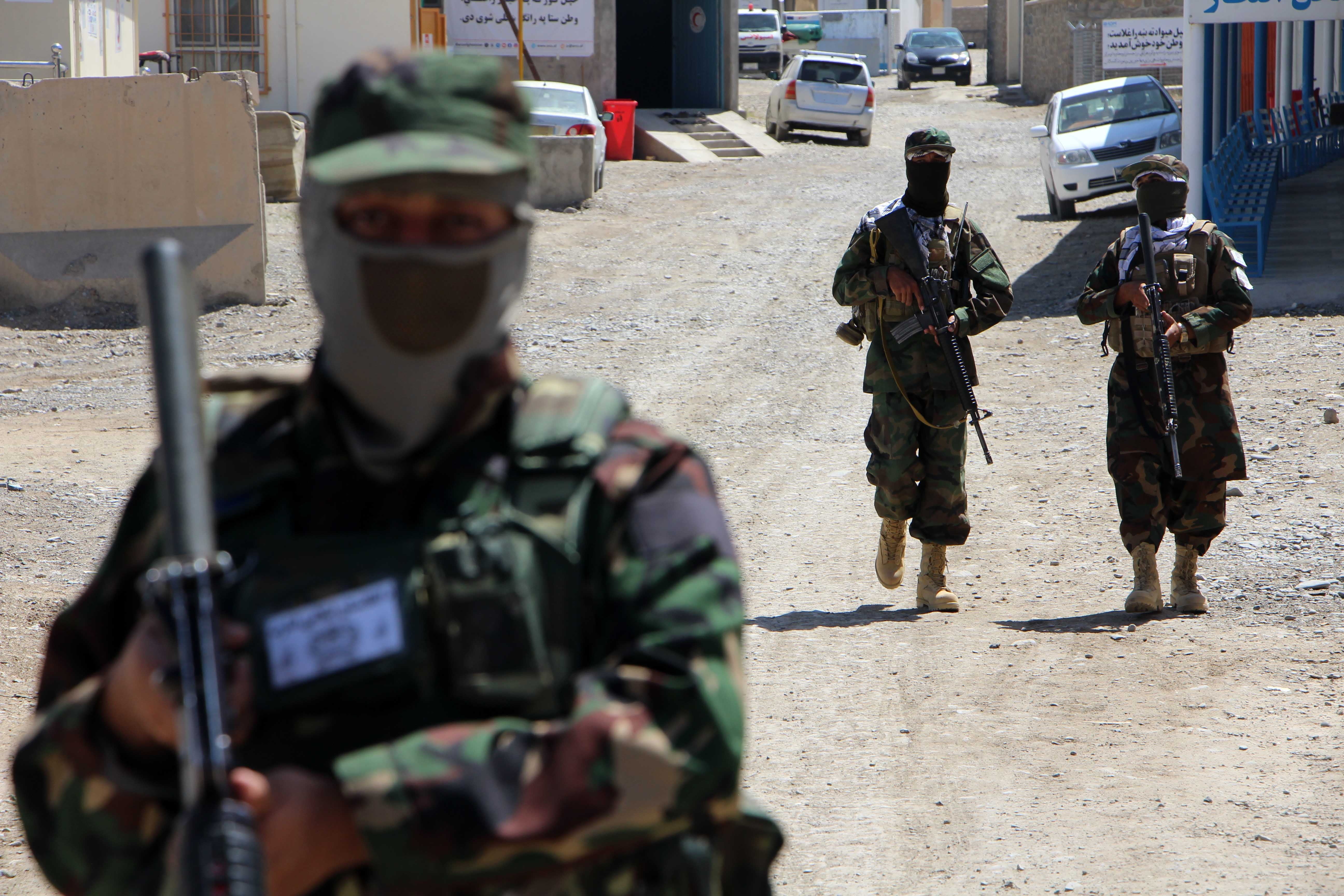 Taliban security stand guard as Afghan refugees returning from neighboring Pakistan arrive at a medical camp near the border in Kandahar, Afghanistan on May 3