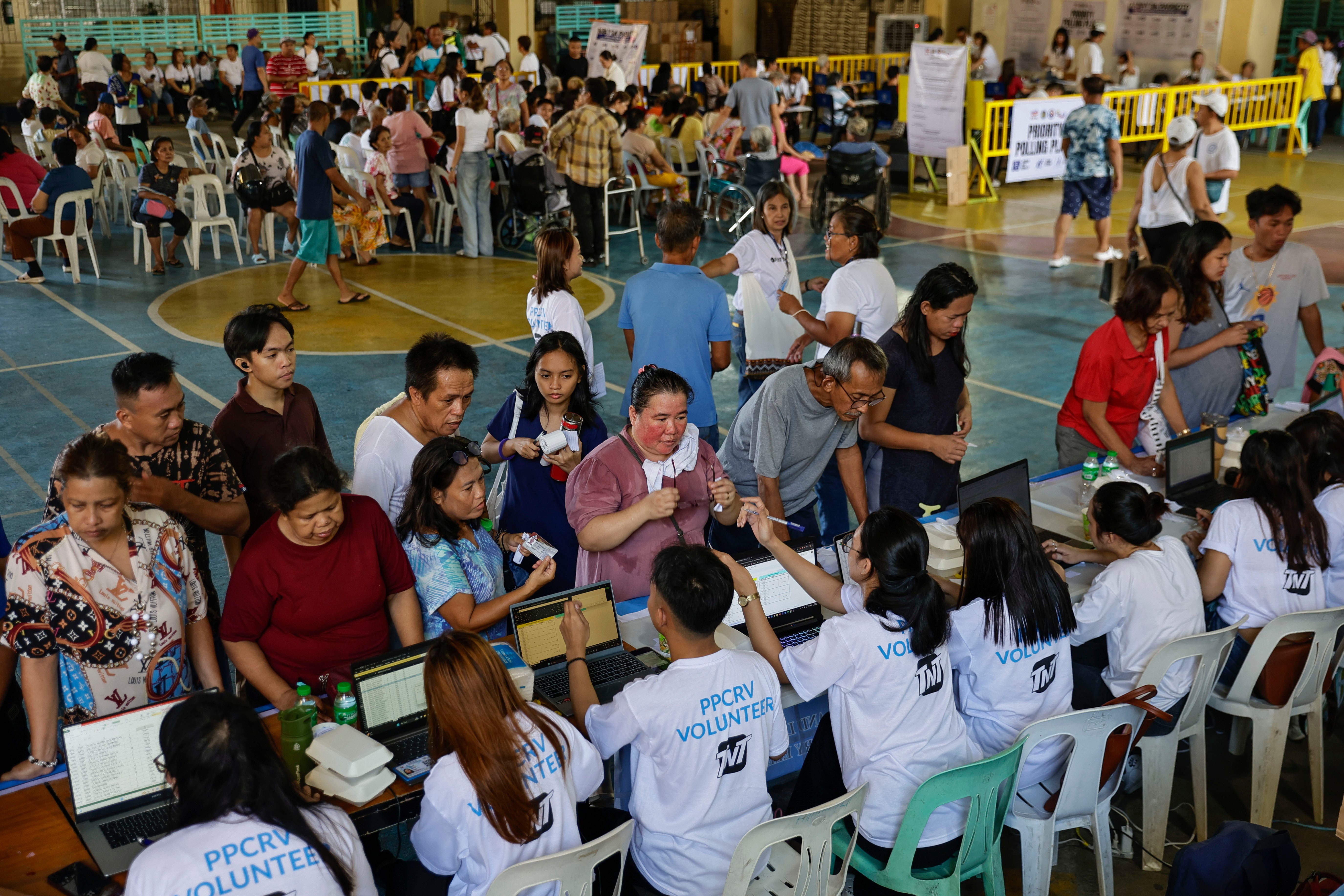 Filipinos consult polling volunteers to find their voting precincts at a school used as a voting center in Quezon City, Metro Manila, Philippines