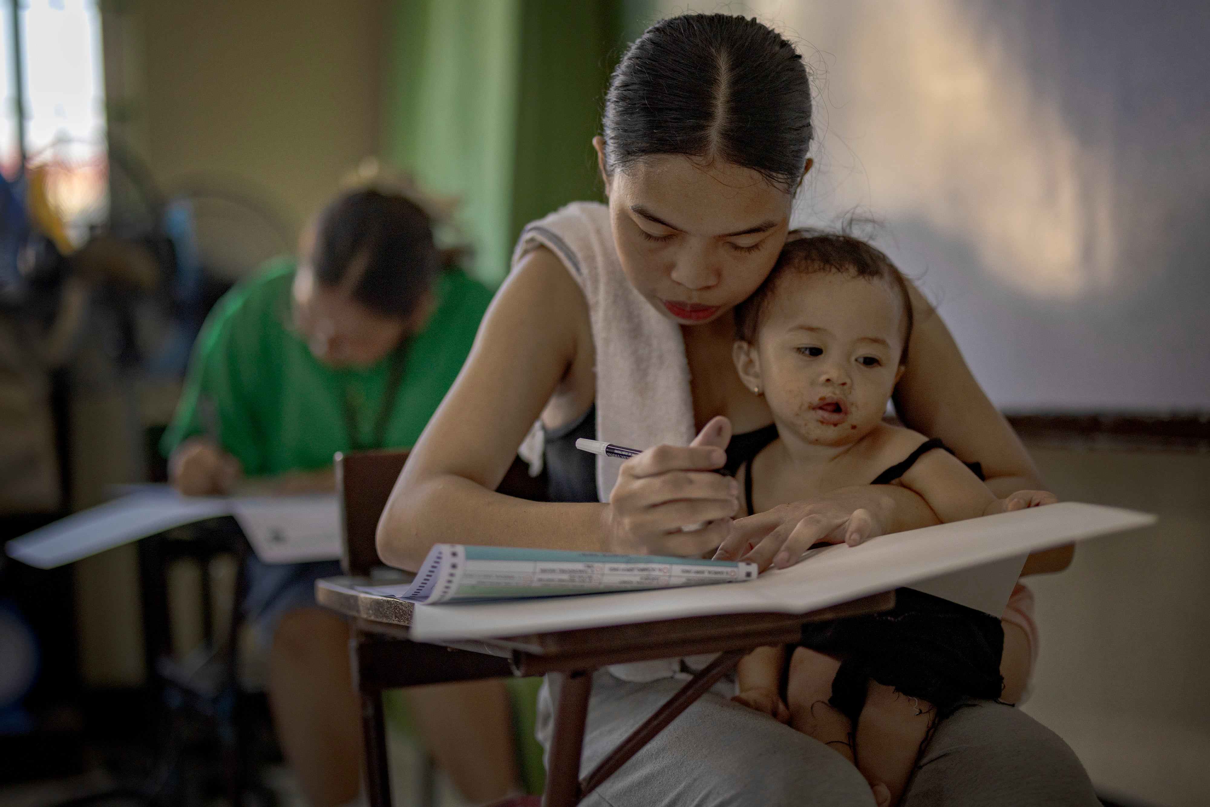 A woman carries her baby as she casts her vote for the midterm elections at a school converted into a polling precinct