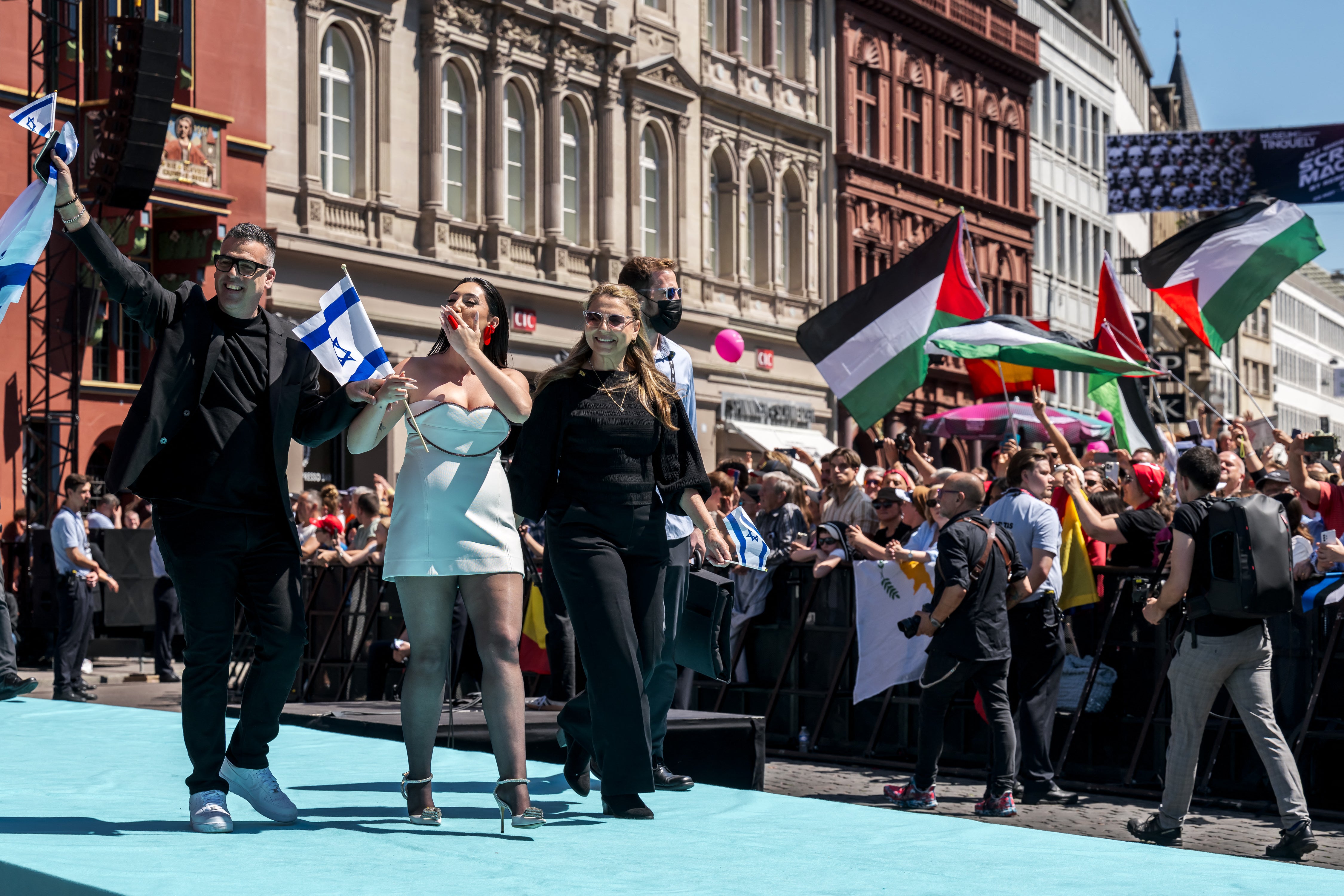 Israel's contestant Yuval Raphael walks the turquoise carpet as pro-Palestine protestors wave flags from the crowds