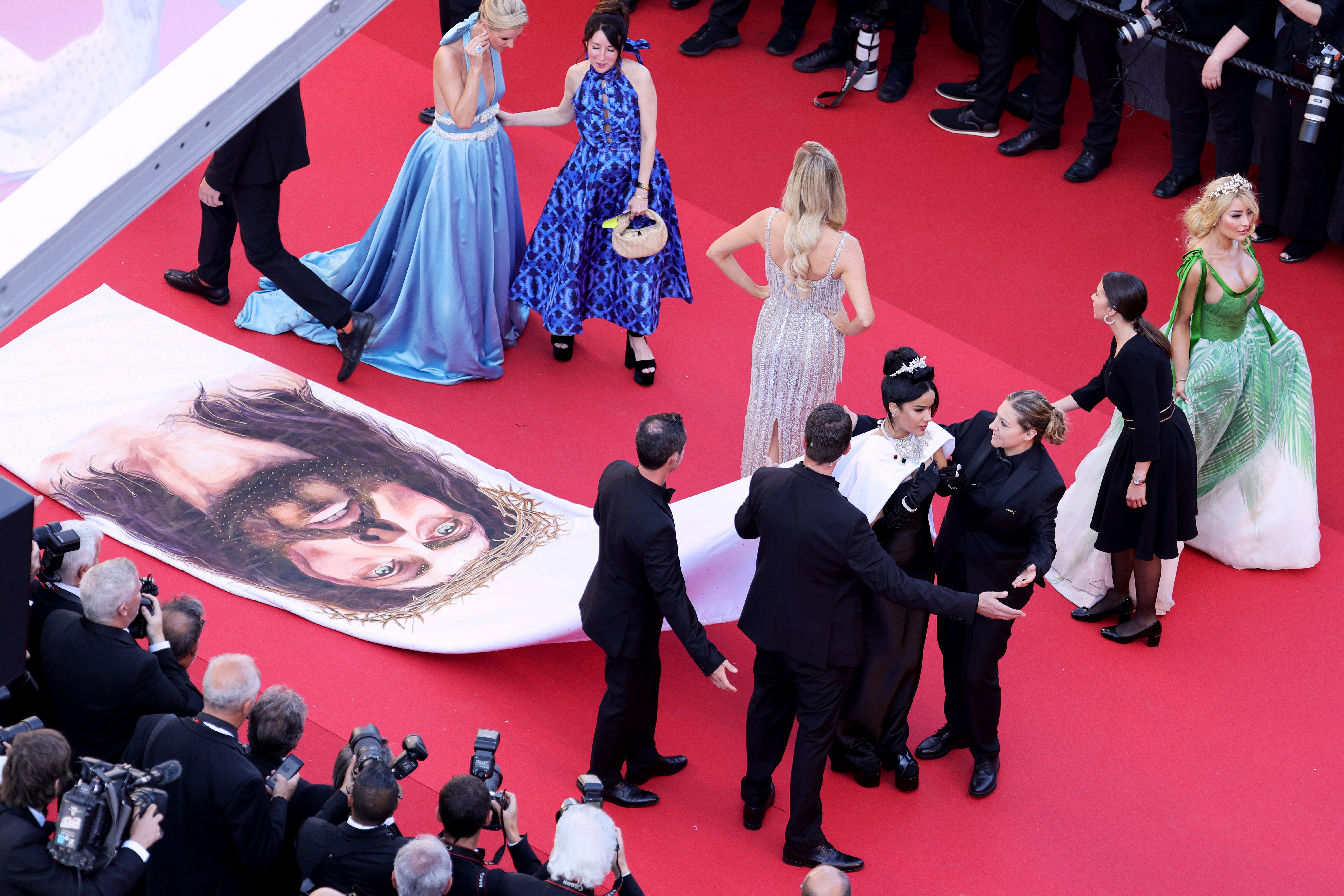 Massiel Taveras walking the 2024 Cannes Film Festival red carpet, flanked by security guards