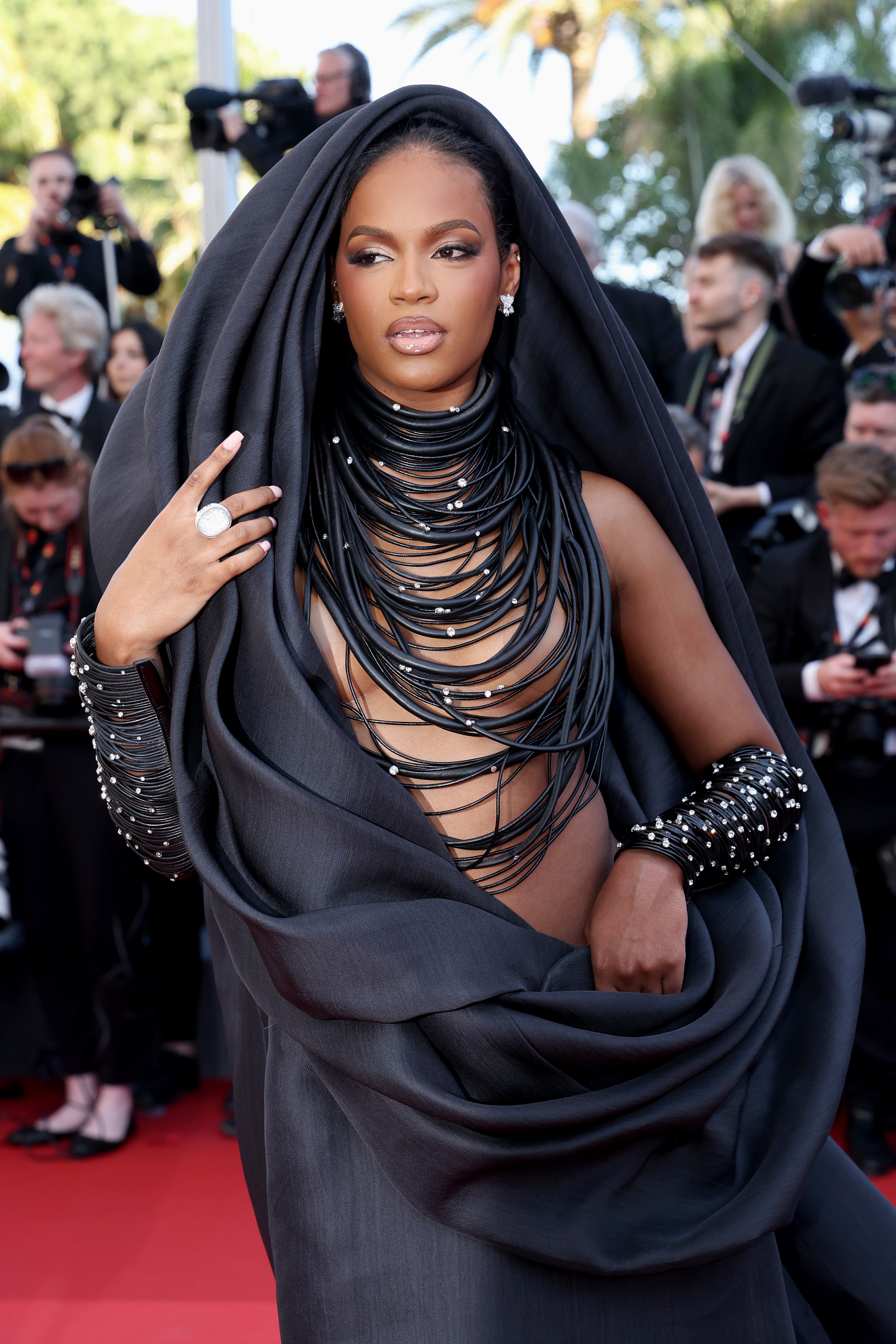 The 25-year-old’s gown included an enlarged neck hole that extended around her head like a hood and down her side. Her naked front was covered by only delicate strings of black beads