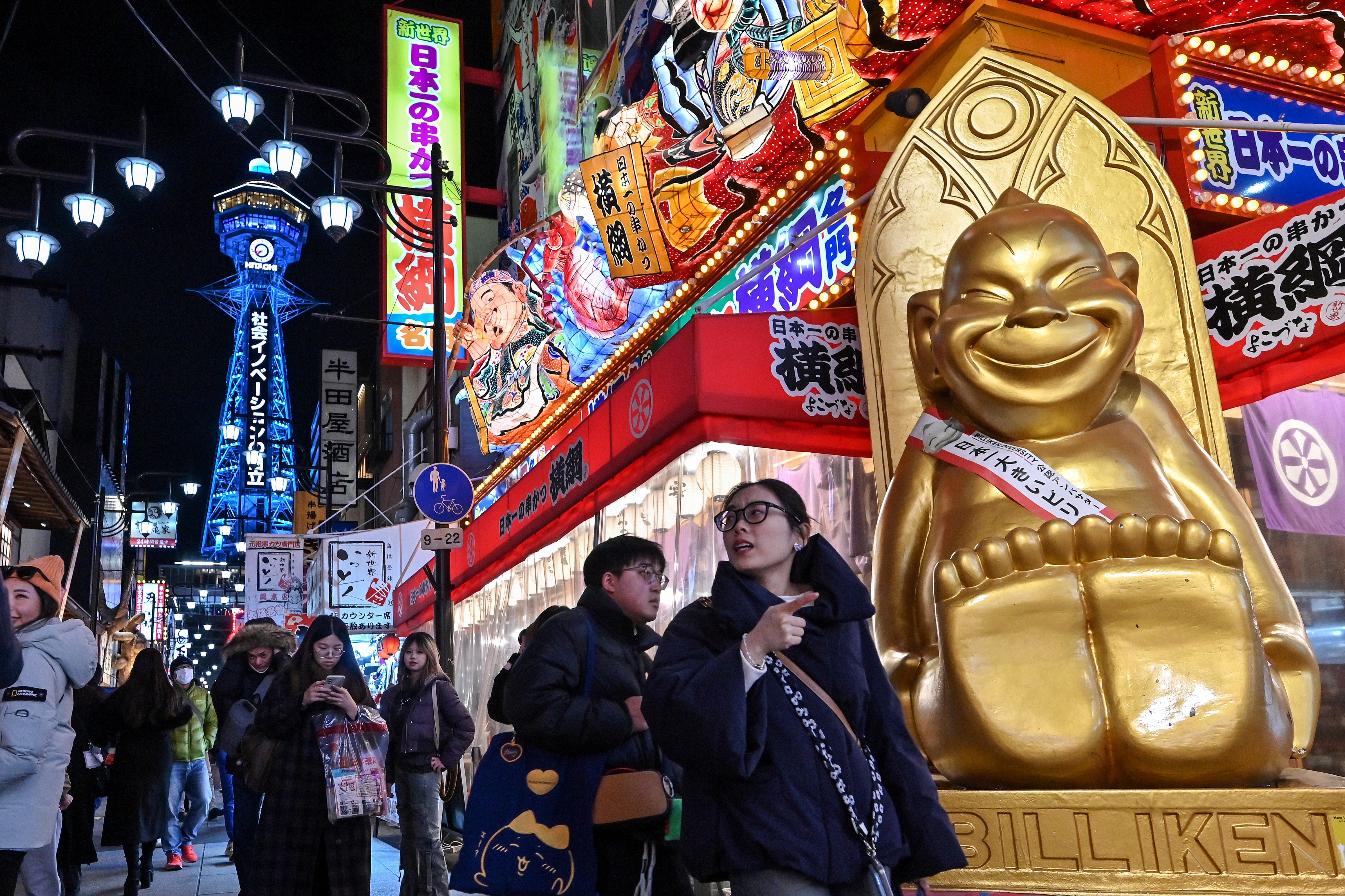 File: Tourists walk past shops and restaurants in the popular Shinsekai district of Osaka