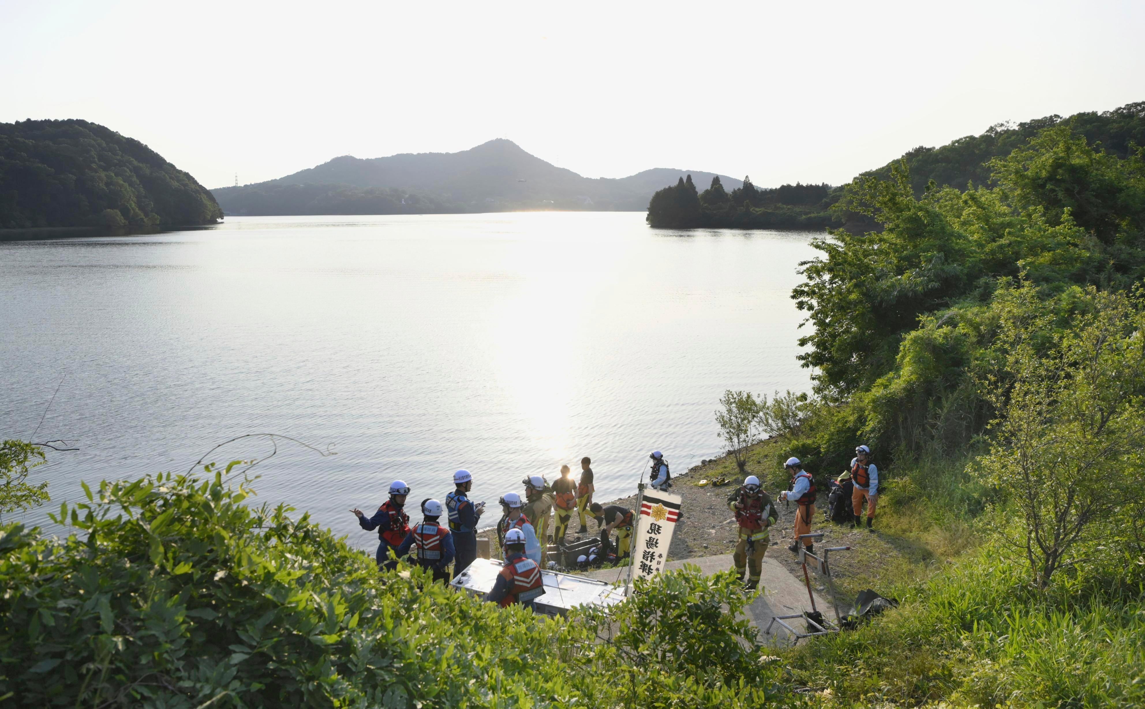Firefighters gather for a search operation as a Japanese air force plane crashed after taking off for a training flight, at a pond in Inuyama, central Japan, Wednesday, May 14, 2025