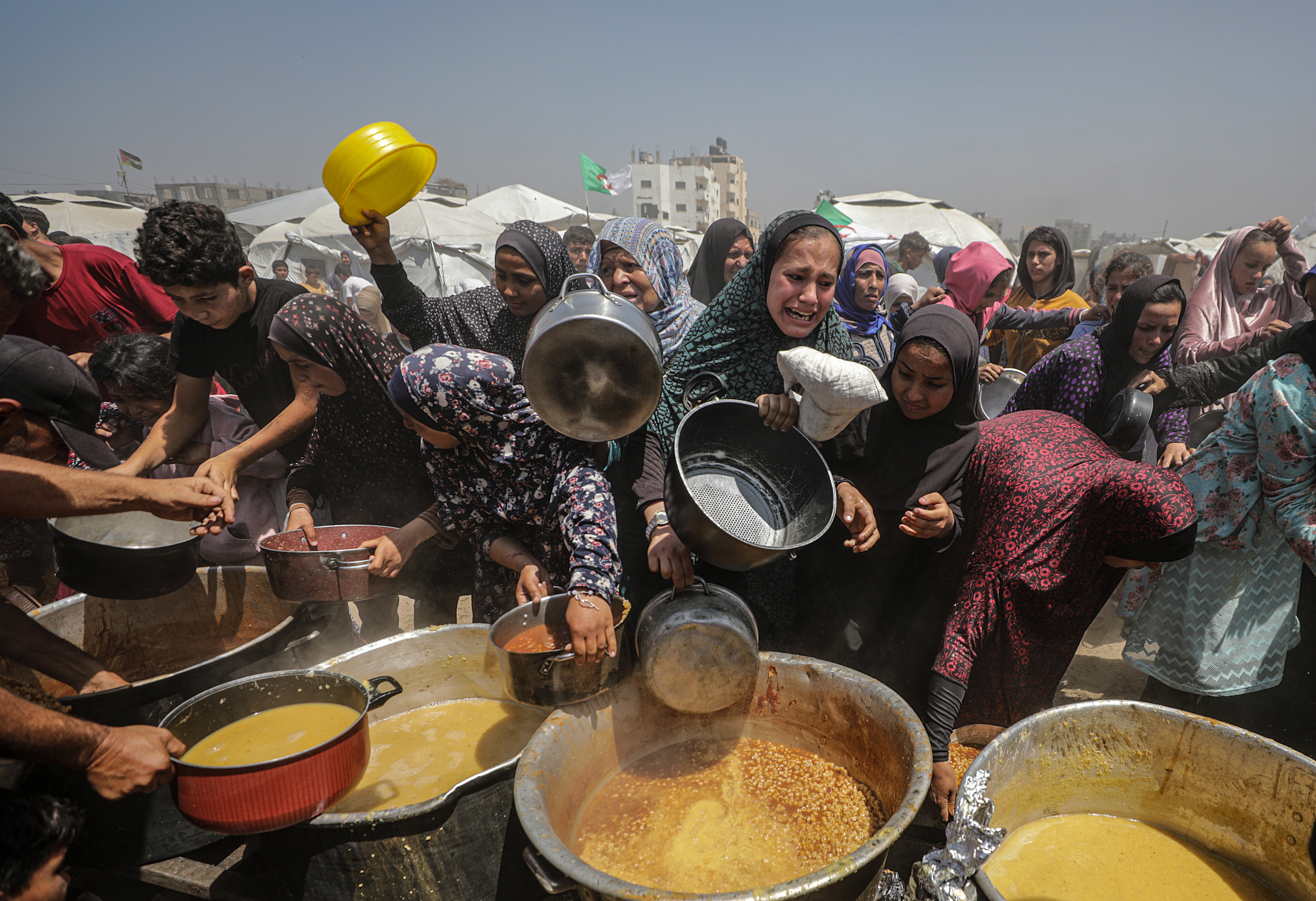 Internally displaced Palestinians gather to receive a portion of food from a charity kitchen, in Jabalia refugee camp, northern Gaza
