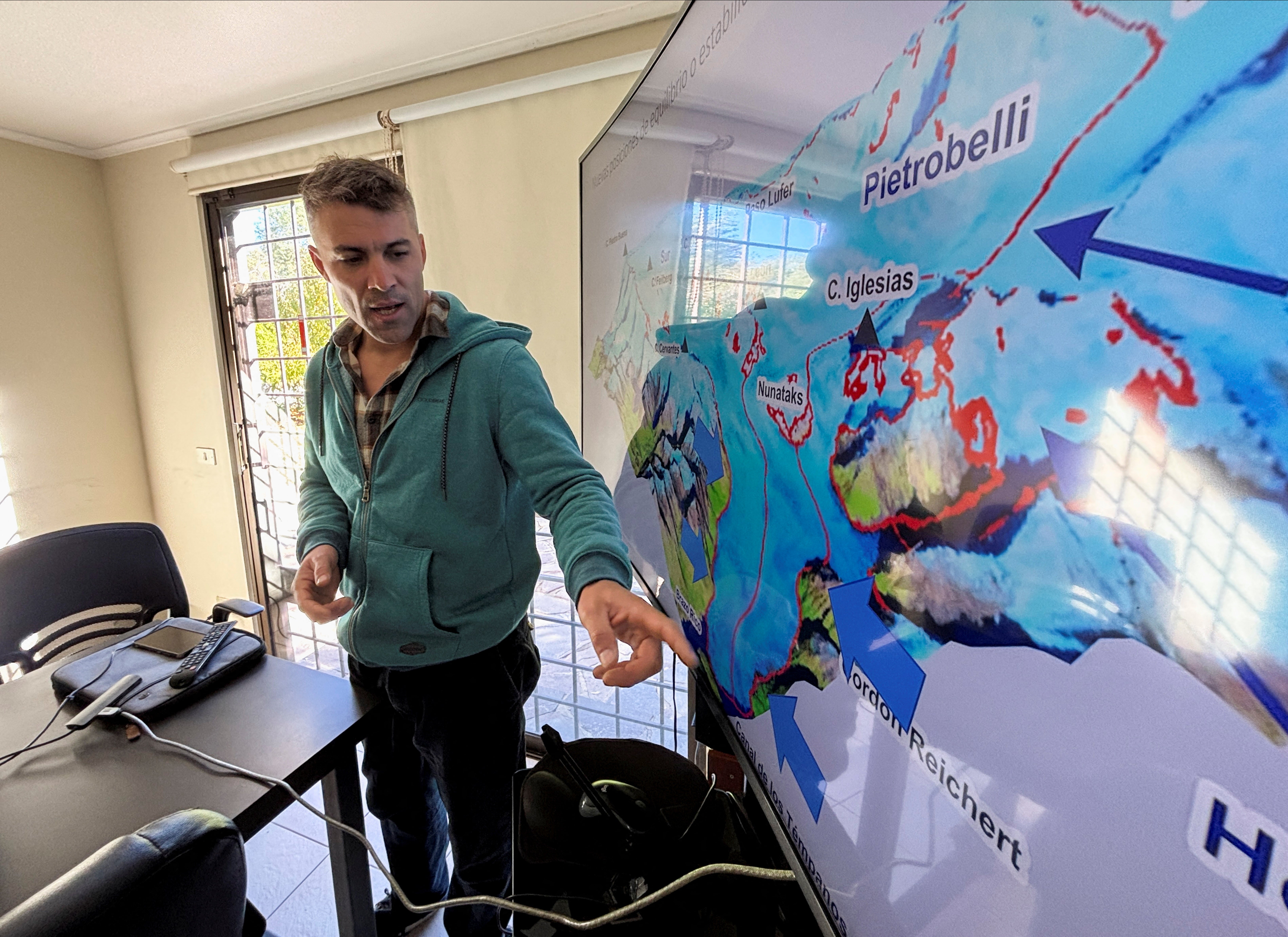 Glaciologist Lucas Ruiz points to a map