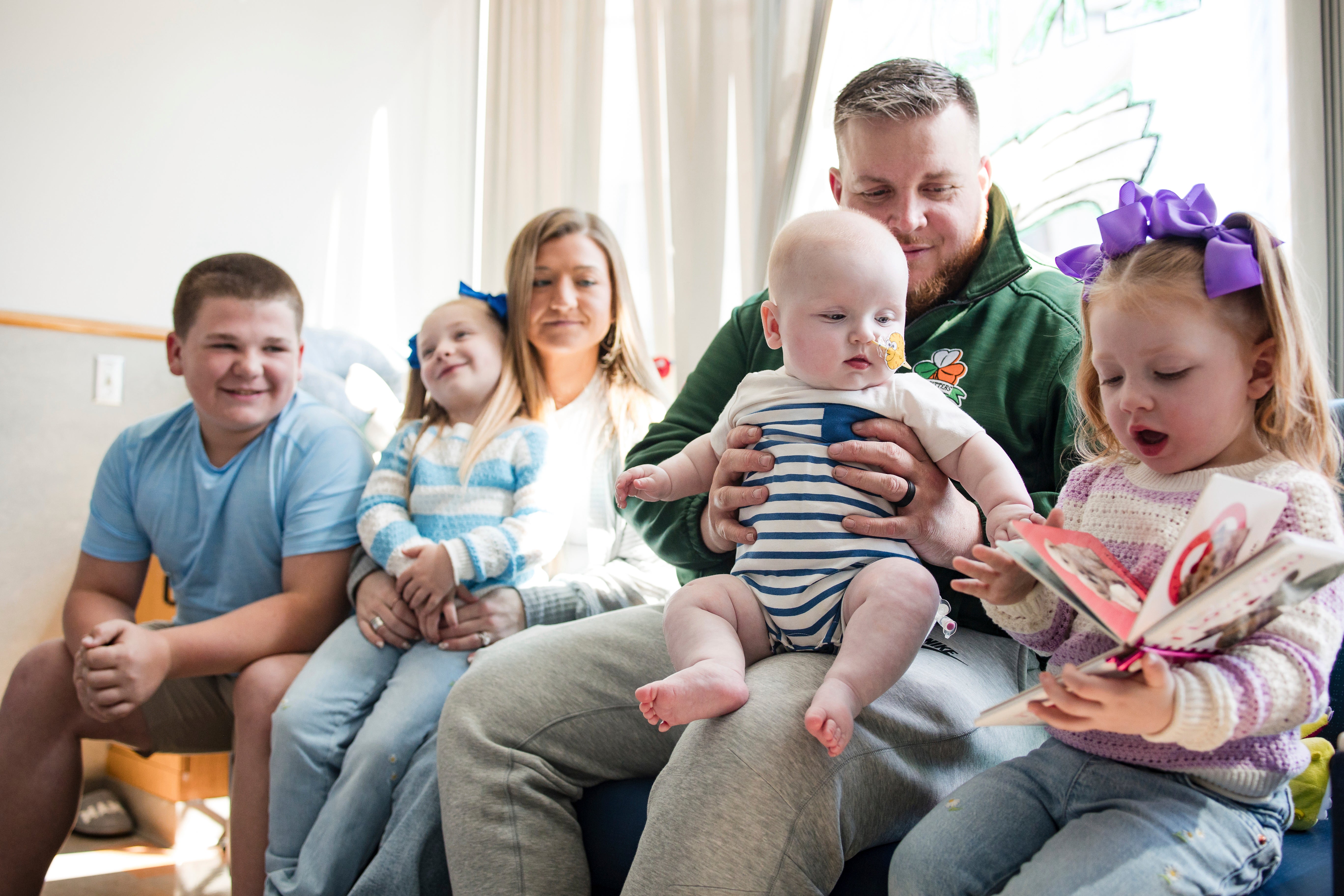 KJ Muldoon sits with his parents, Kyle and Nicole Muldoon, and his siblings after a follow-up dose of an experimental gene editing treatment at the hospital in April 2025