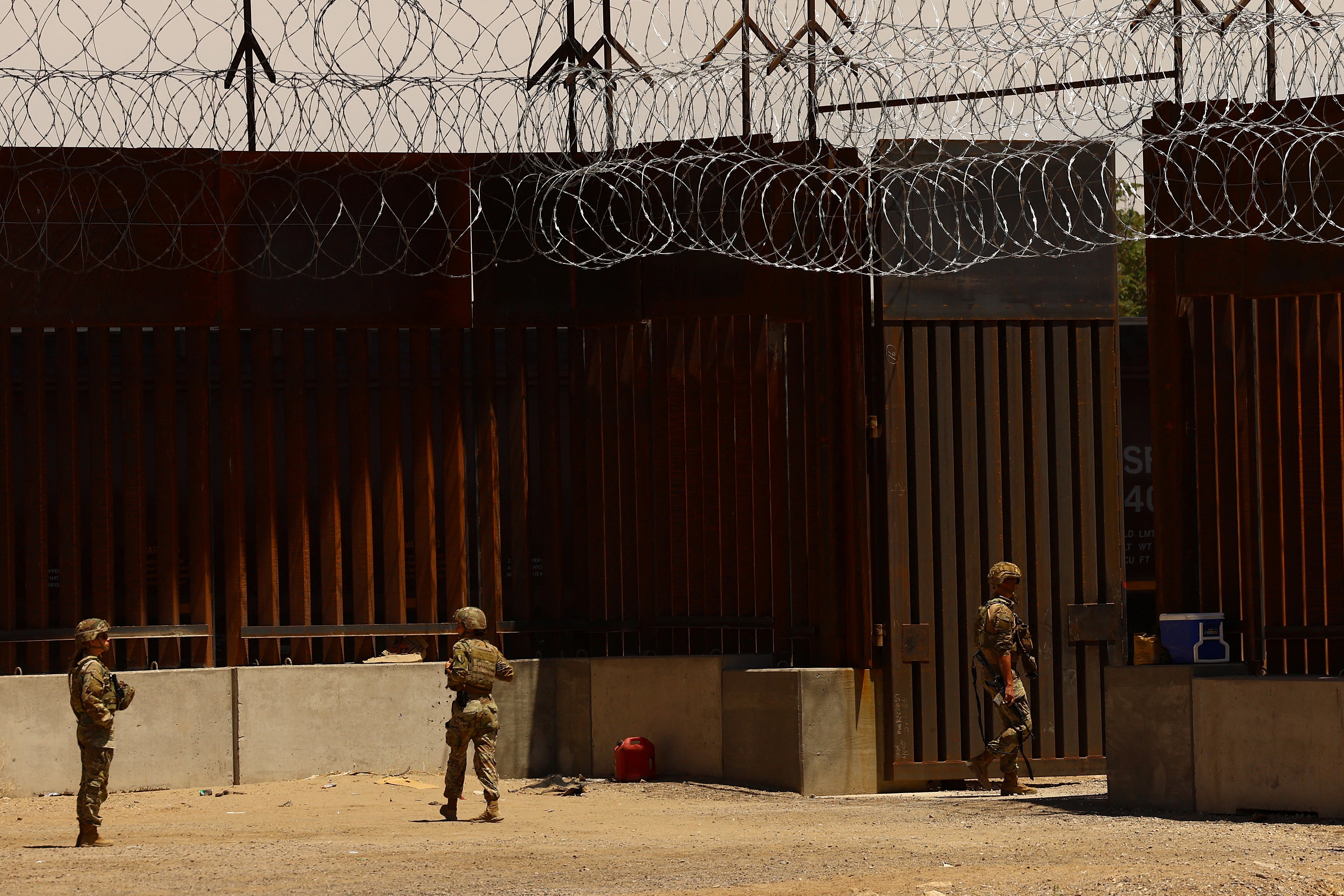 U.S. military personnel stand near the wall on the U.S.-Mexico border as President Donald Trump completes his first 100 days in office
