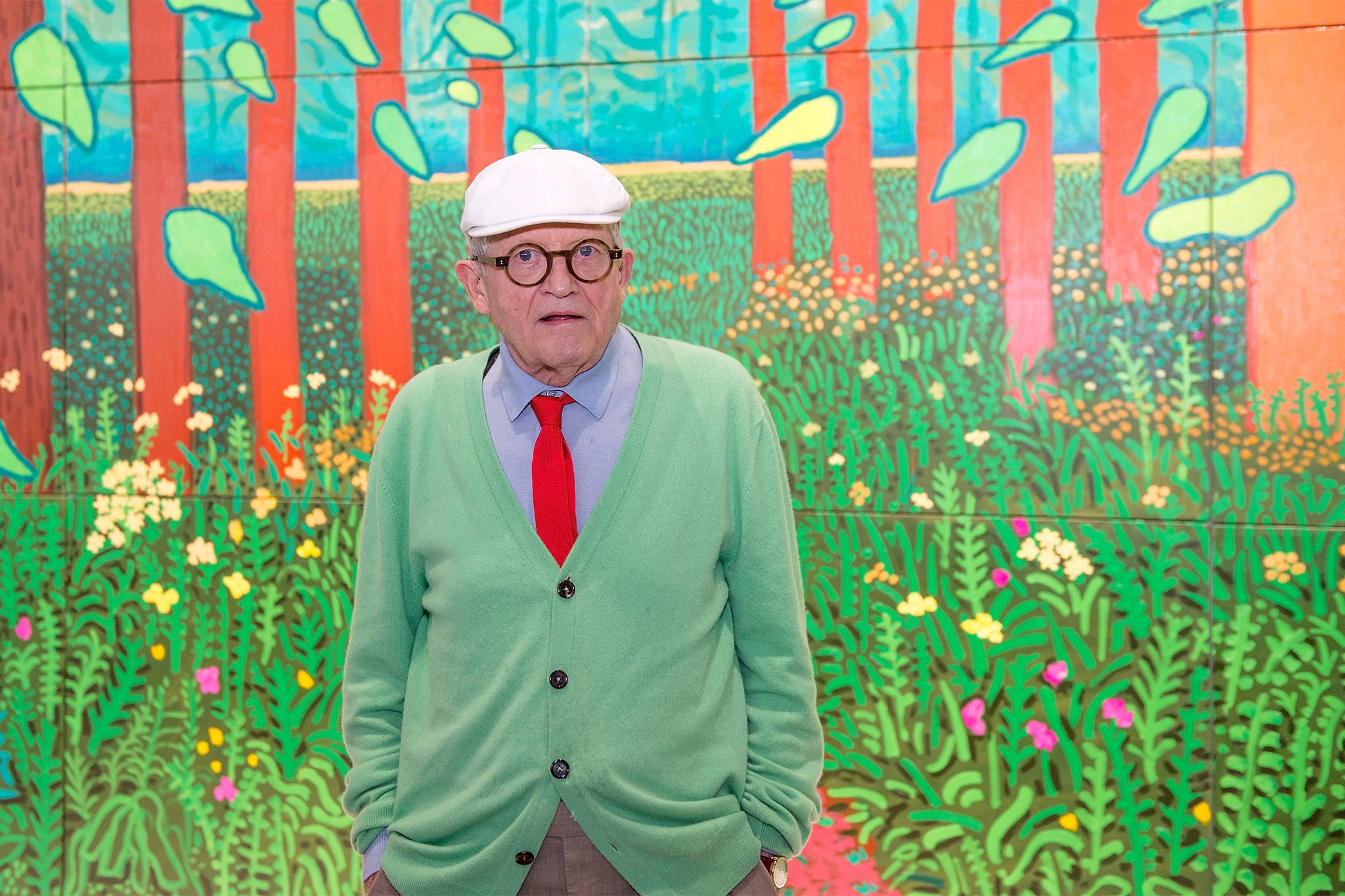 David Hockney poses in front of his painting, ‘The Arrival of Spring in Woldgate, East Yorkshire in 2011’