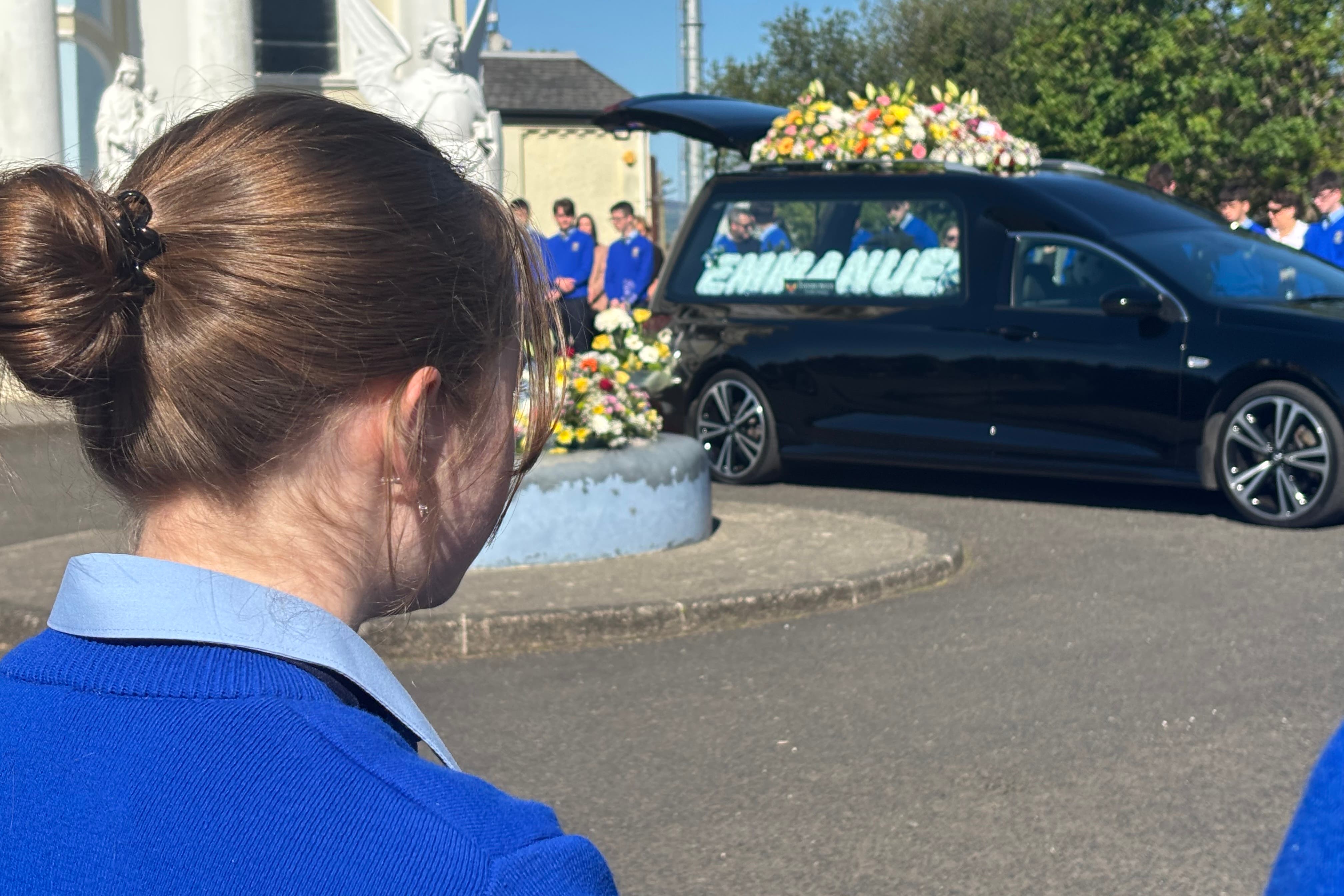A schoolgirl forms part of a guard of honour outside St Mary’s Oratory in Buncrana ahead of the funeral of teenager Emmanuel Familola (Rebecca Black/PA)