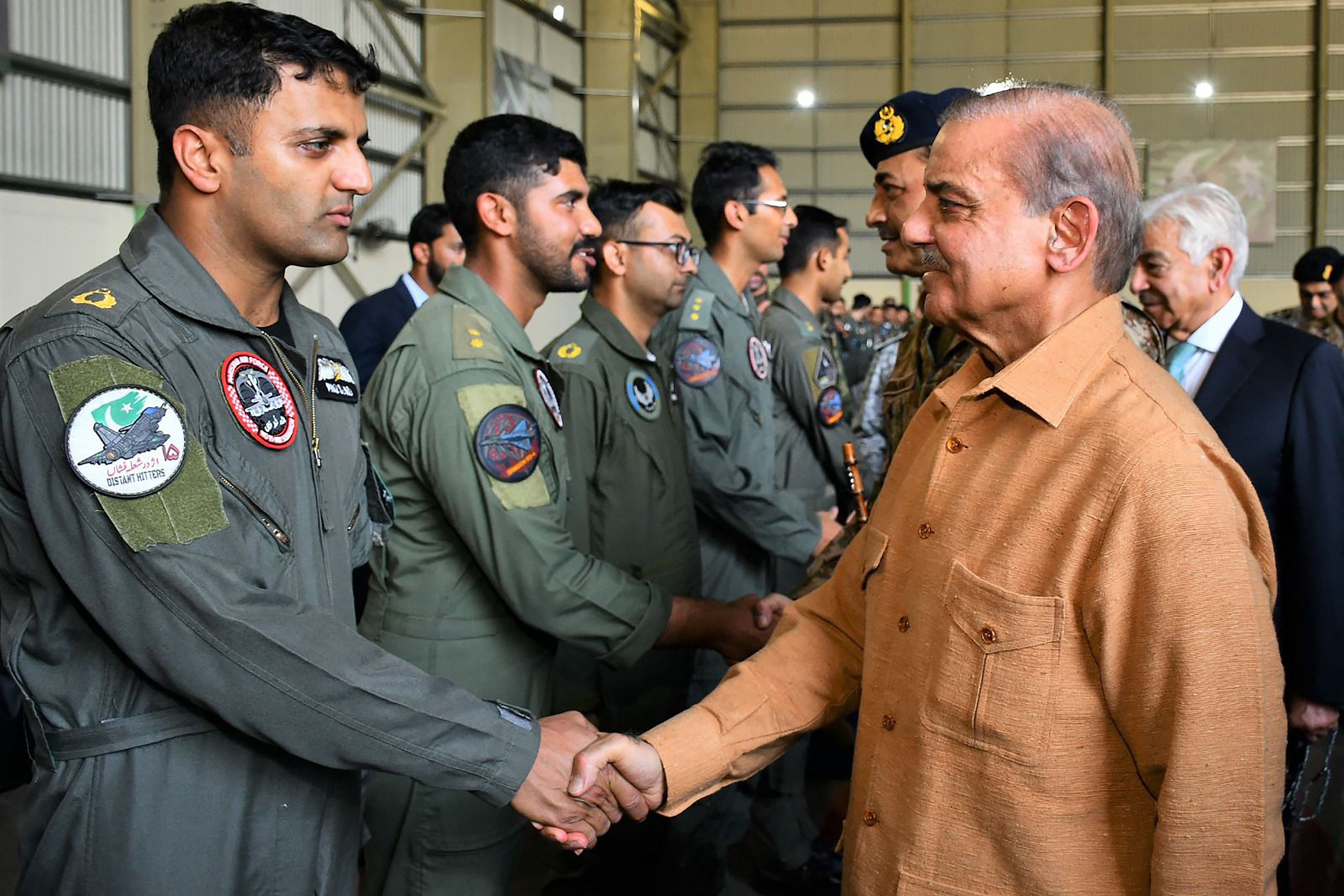 In this handout photo taken and released by Pakistan's Inter-Services Public Relations (ISPR), on May 15, 2025, Pakistan's Prime Minister Shehbaz Sharif (R) greets pilots during a visit to Pakistan Air Force's base at Kamra