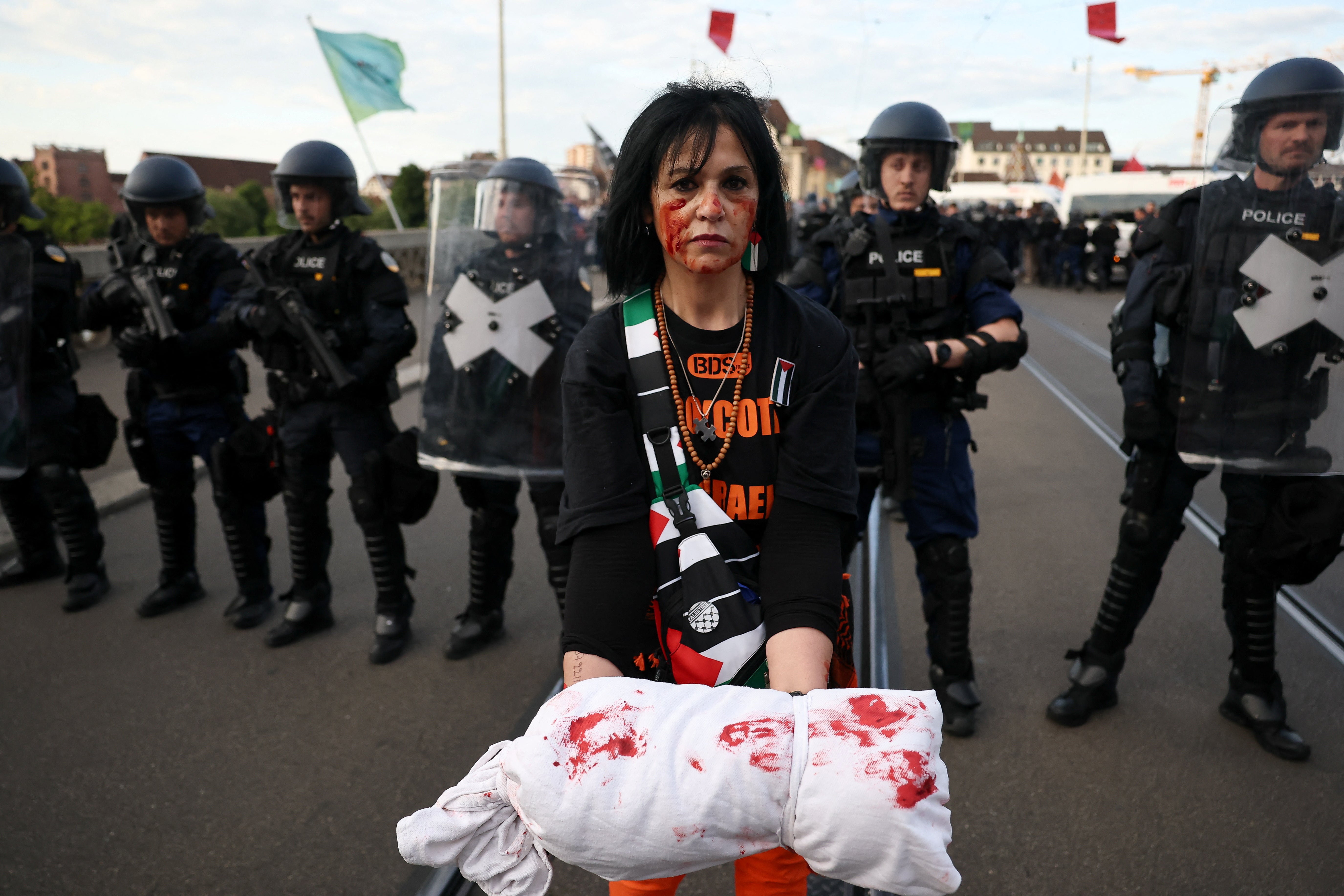 A pro-Palestinian demonstrator holds a prop, representing a body bag, in front of police officers during a protest, on the day of the Grand Final of the 2025 Eurovision Song Contest in Basel, Switzerland
