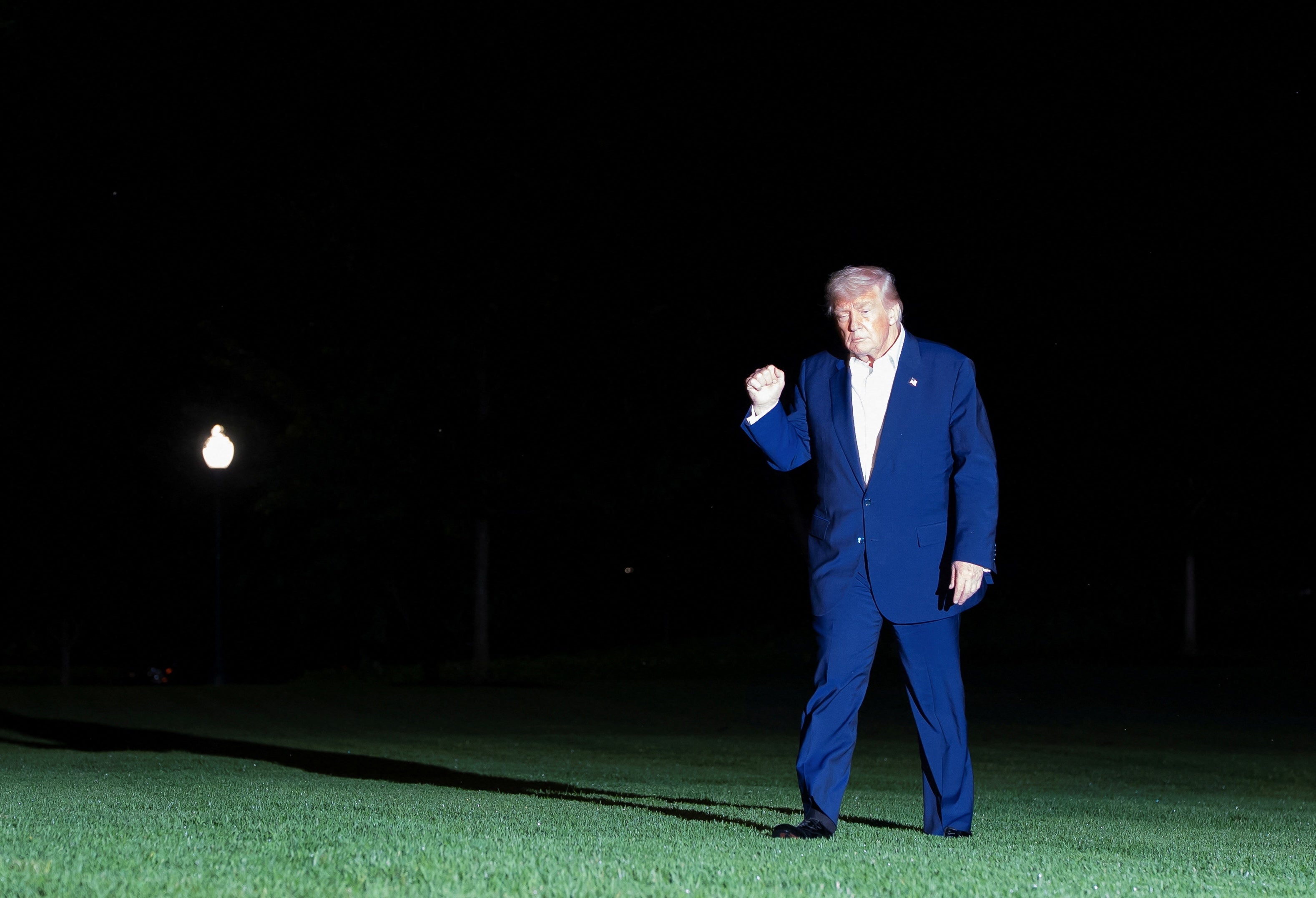President Donald Trump gestures while walking across the South Lawn as he returns to the White House following a trip to the Middle East on Friday