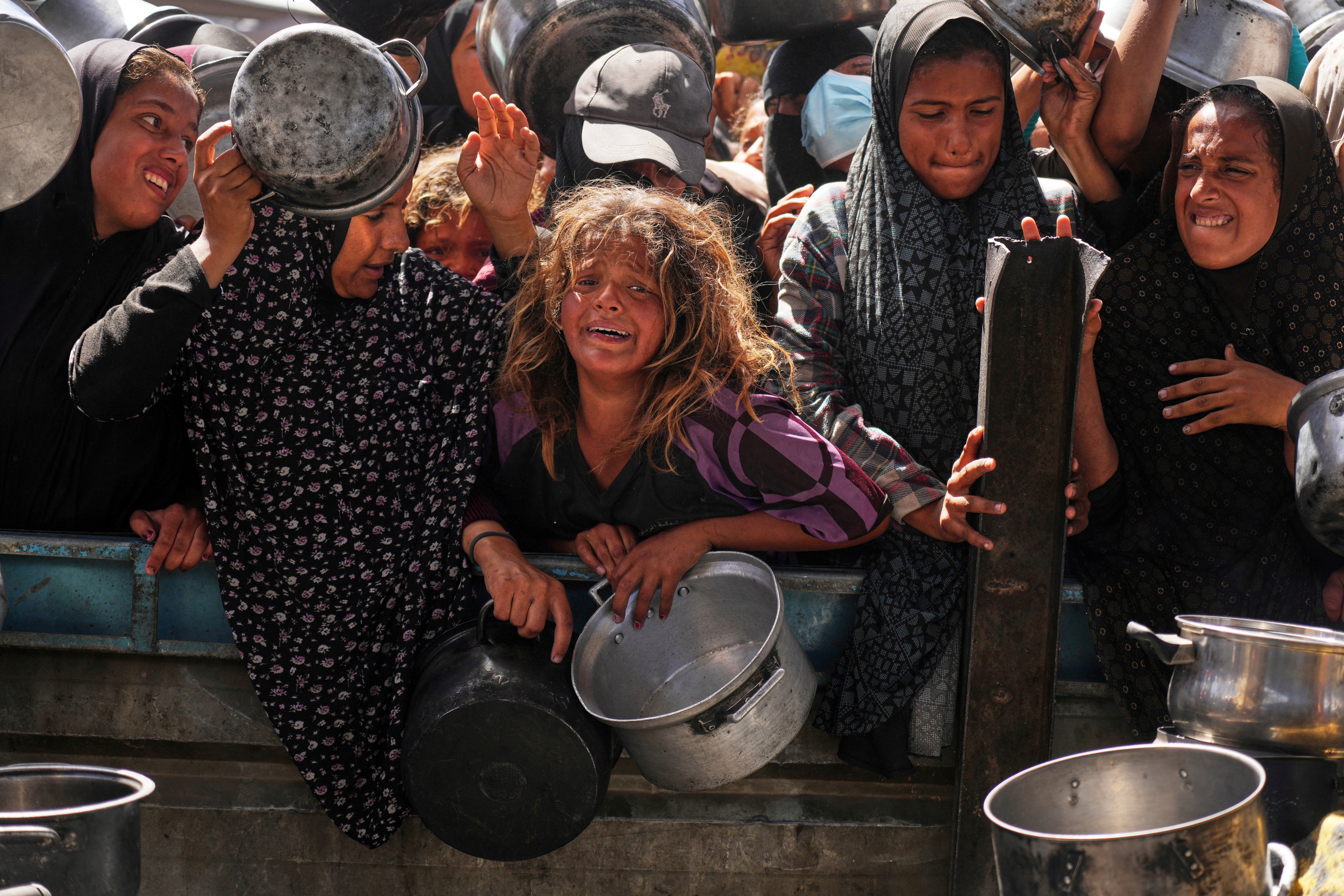 Palestinians struggle to get donated food at a community kitchen in Khan Younis, Gaza Strip