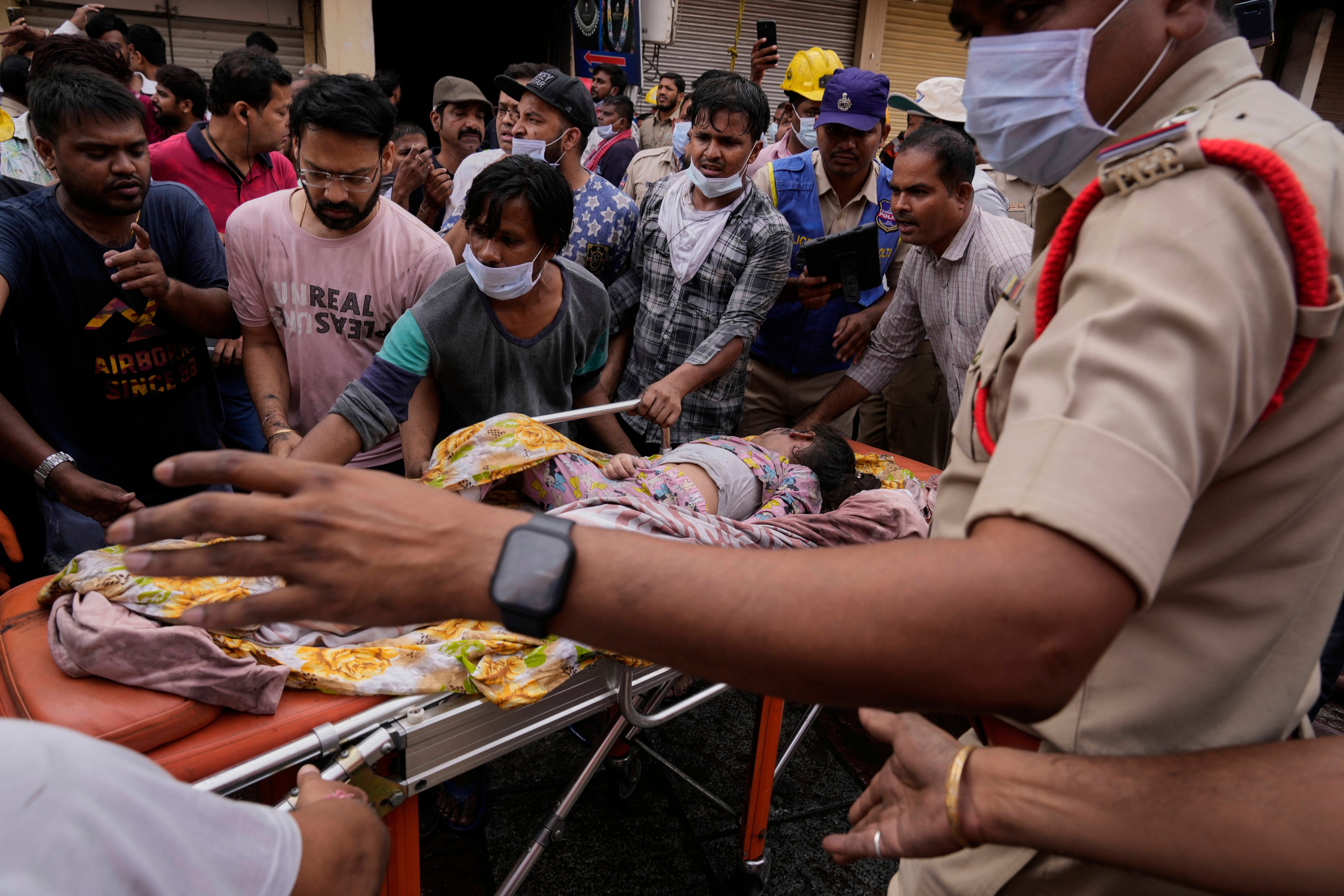 Fire officials rescue an injured person from a building after it caught fire in Hyderabad, India, Sunday