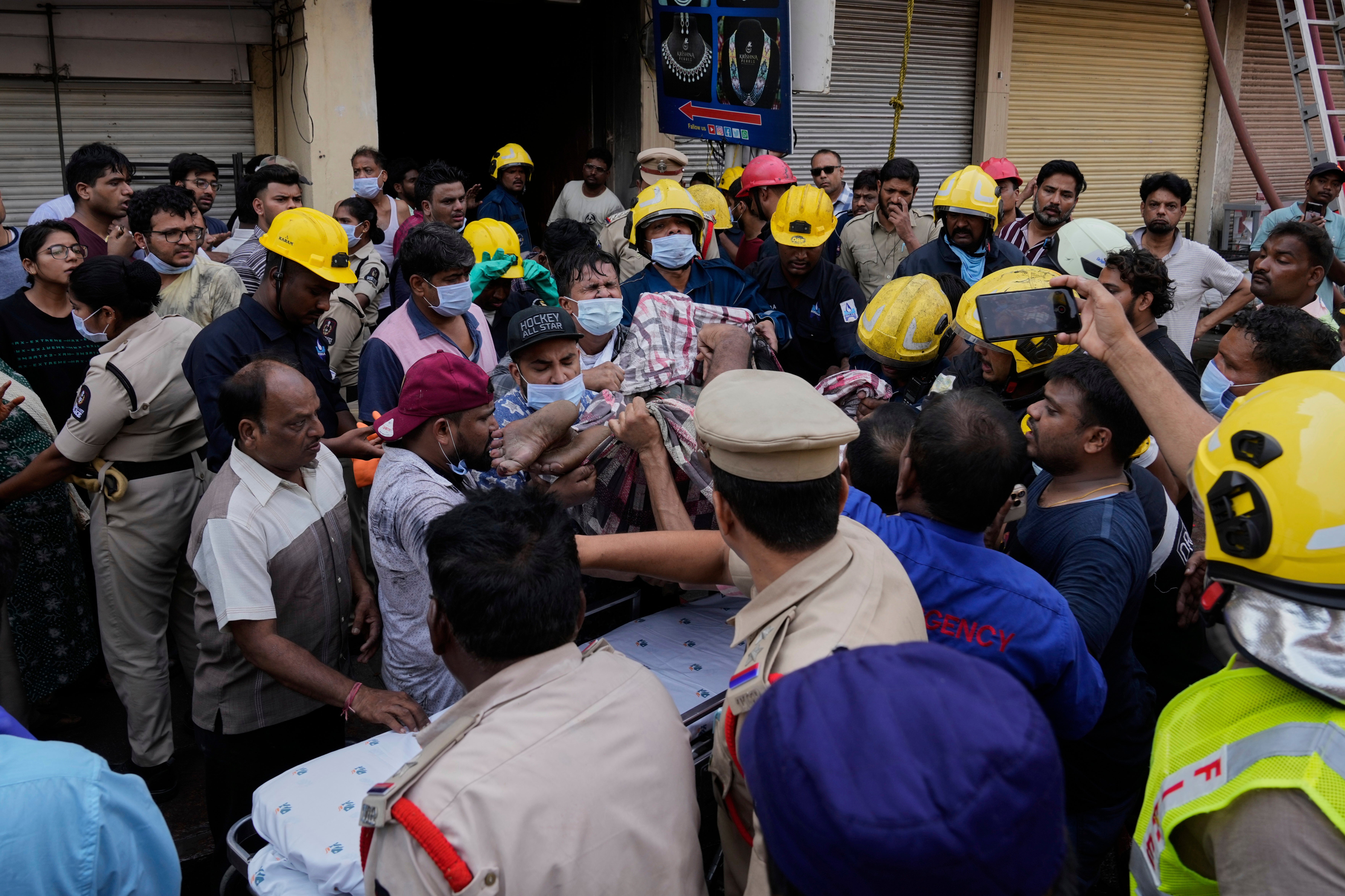 Fire officials rescue an injured person from a building after it caught fire in Hyderabad, India, Sunday