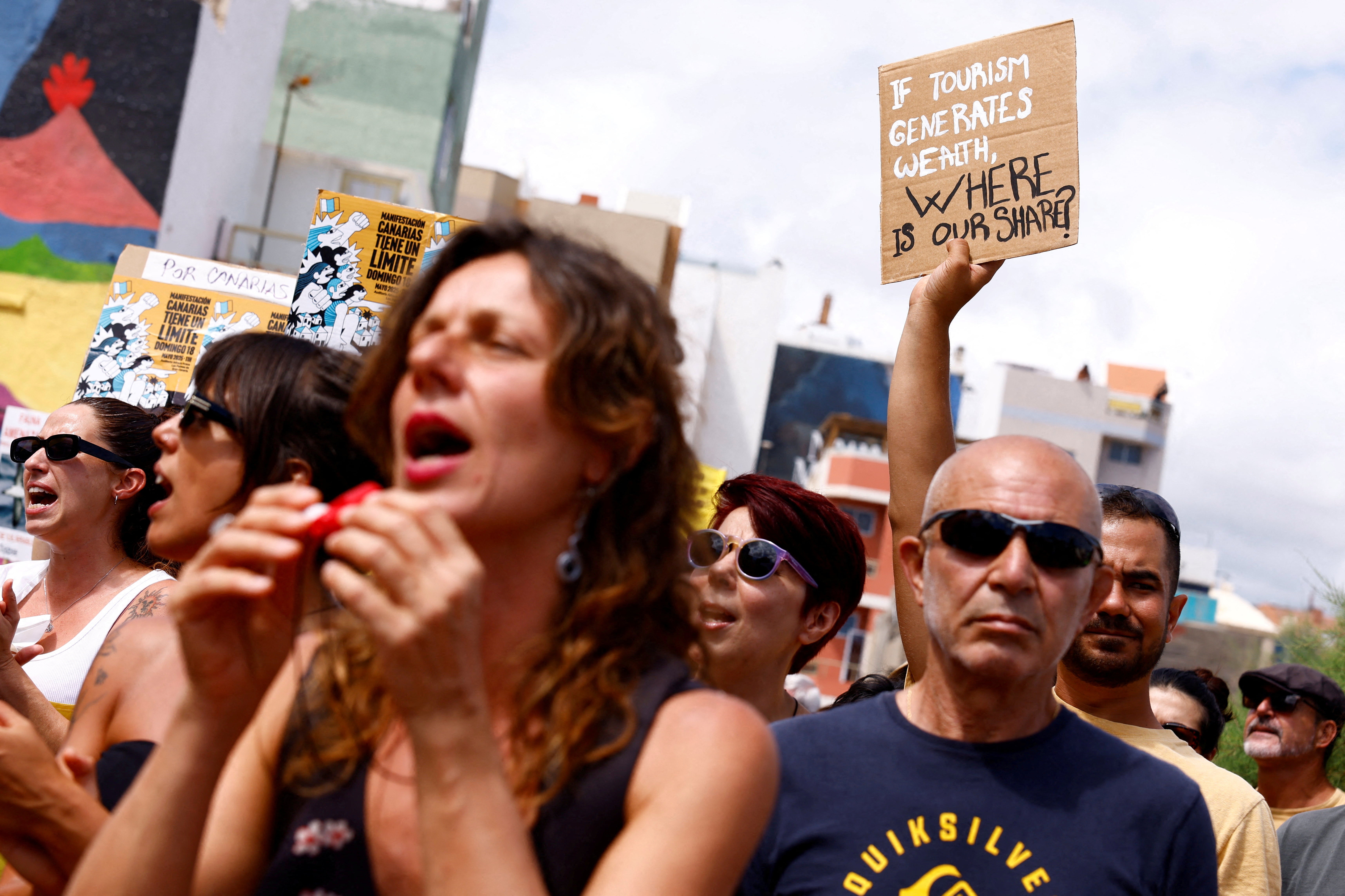 A man holds a sign, reading: ‘If tourism generates wealth, where is our share?’