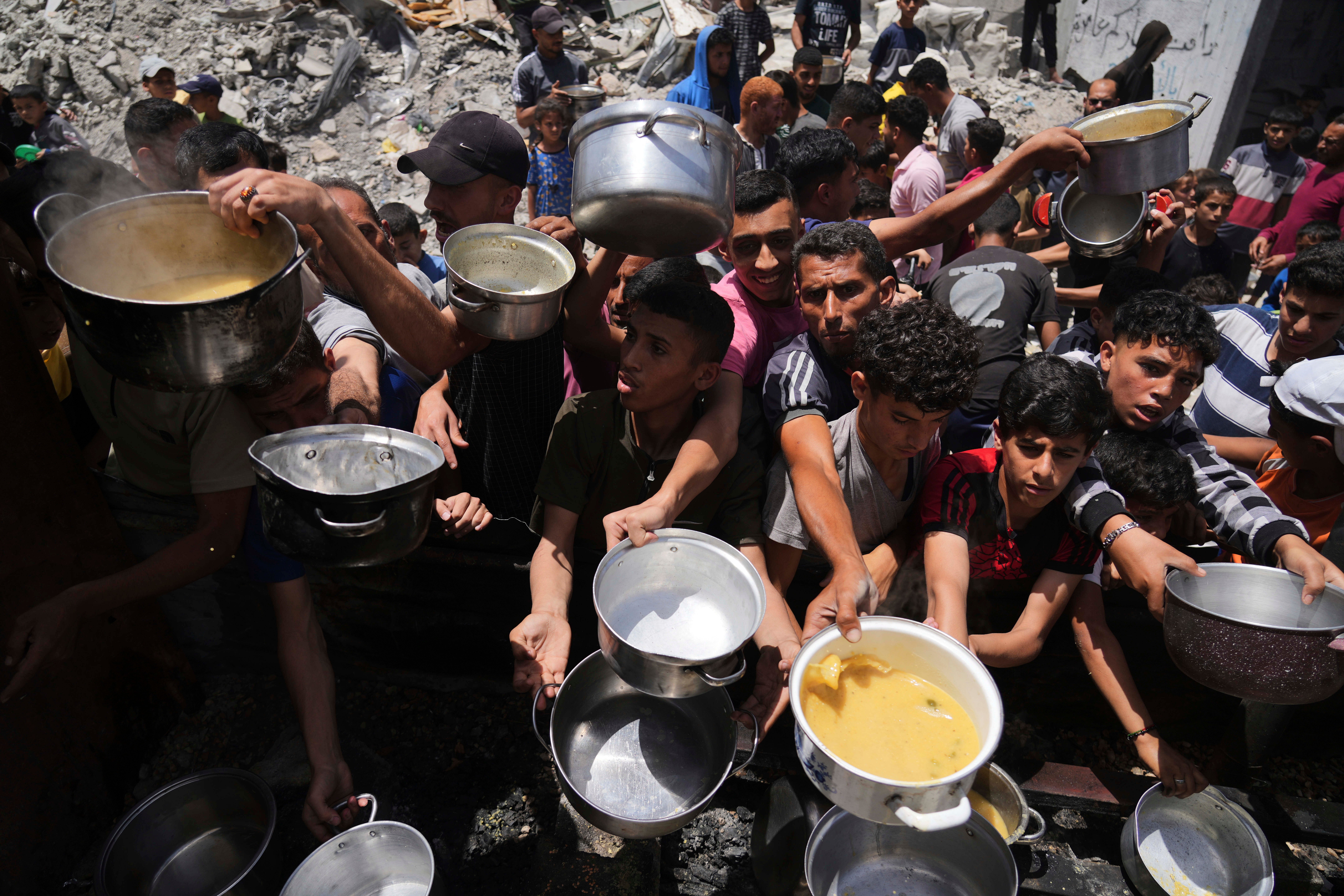 Palestinians struggle to get donated food at a community kitchen in Jabalia, northern Gaza Strip