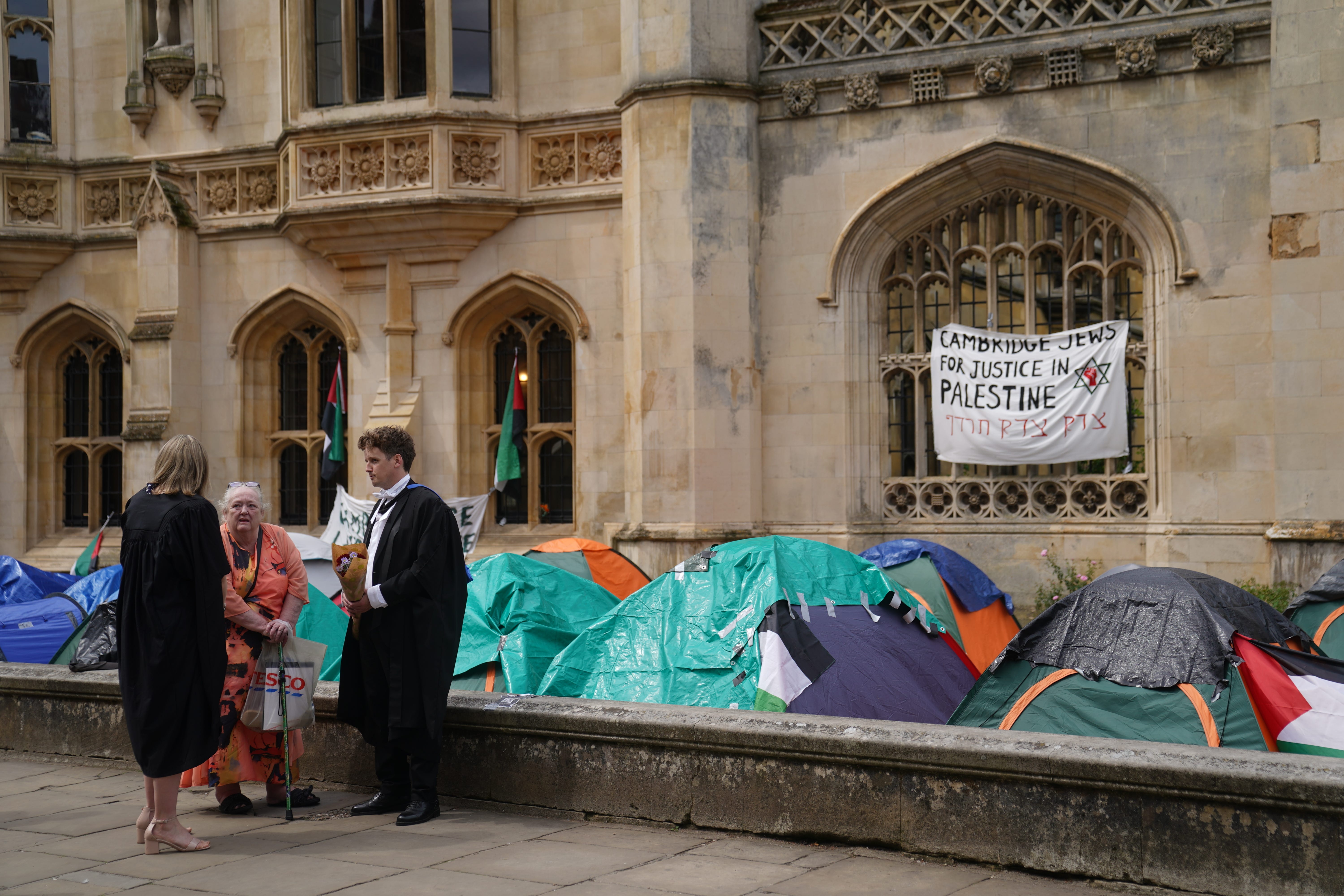 Graduating students stand near an encampment protest over the Gaza conflict on the grounds of Cambridge University (PA)
