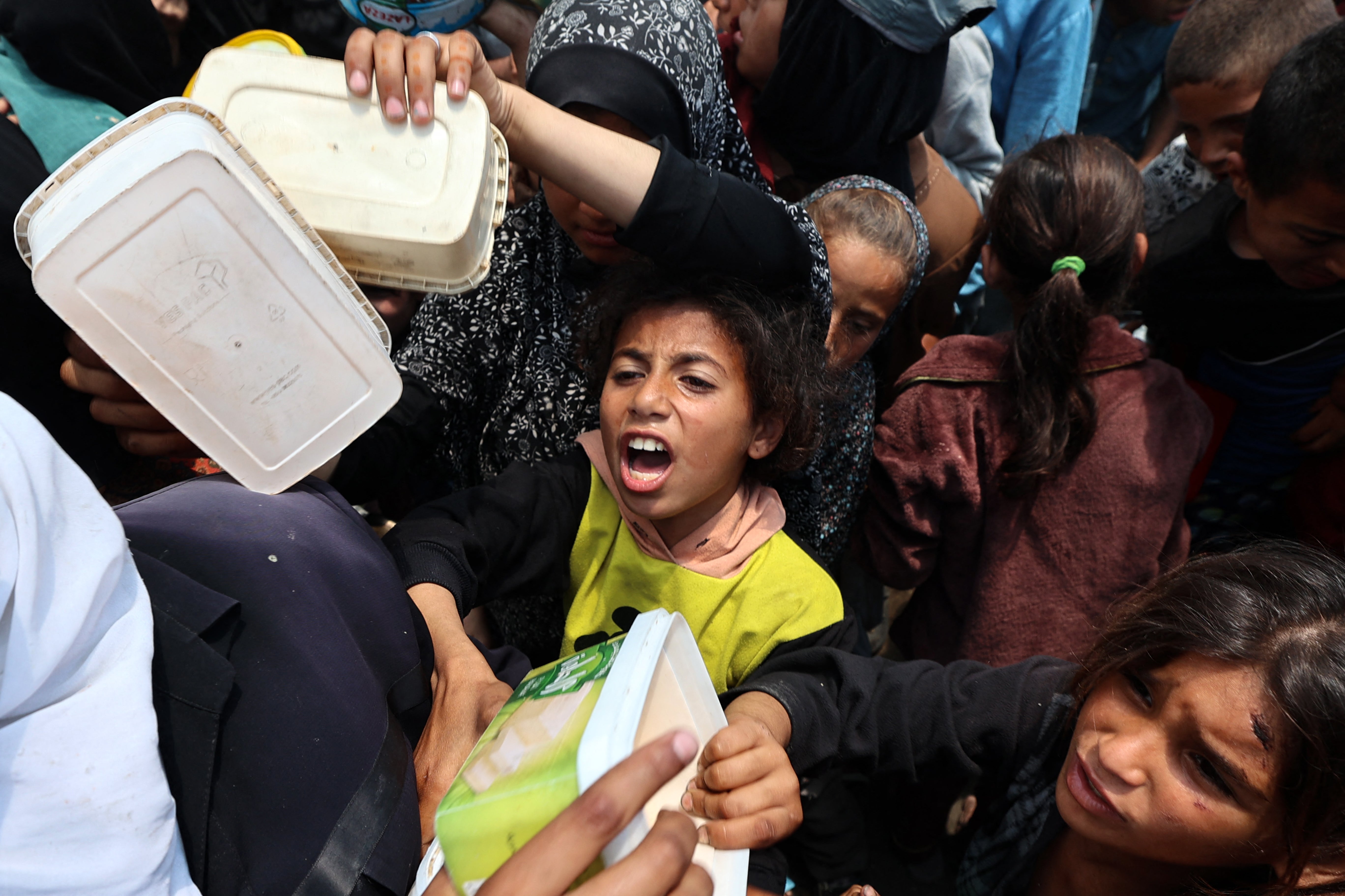 Palestinian children gather for a hot meal at a food distribution point in the Nuseirat camp for refugees in the central Gaza Strip on Wednesday