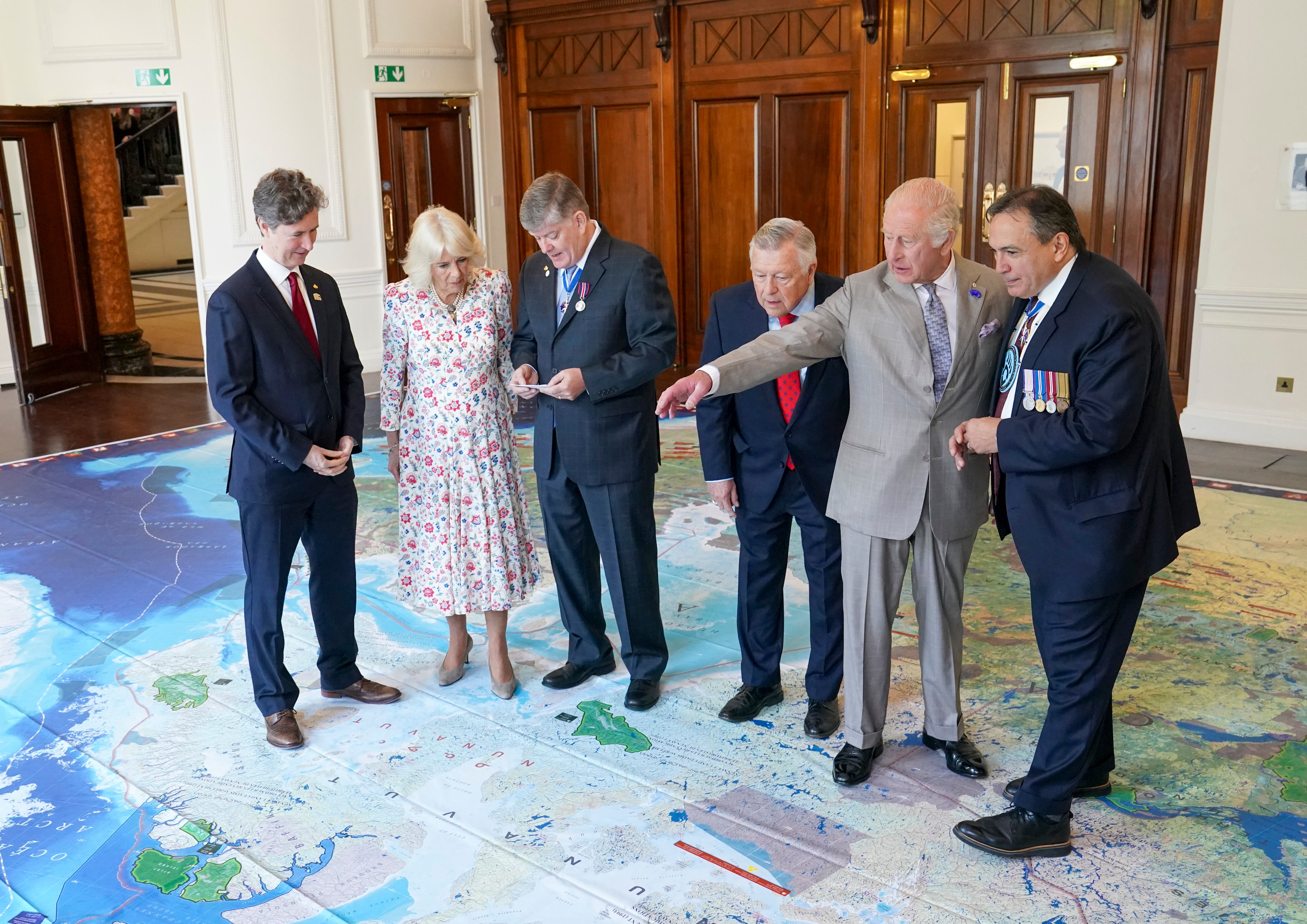 Charles and Camilla view a map of Canada with High Commissioner for Canada Ralph Goodale (third right) and Chief Perry Bellegarde (right) during the visit to Canada House