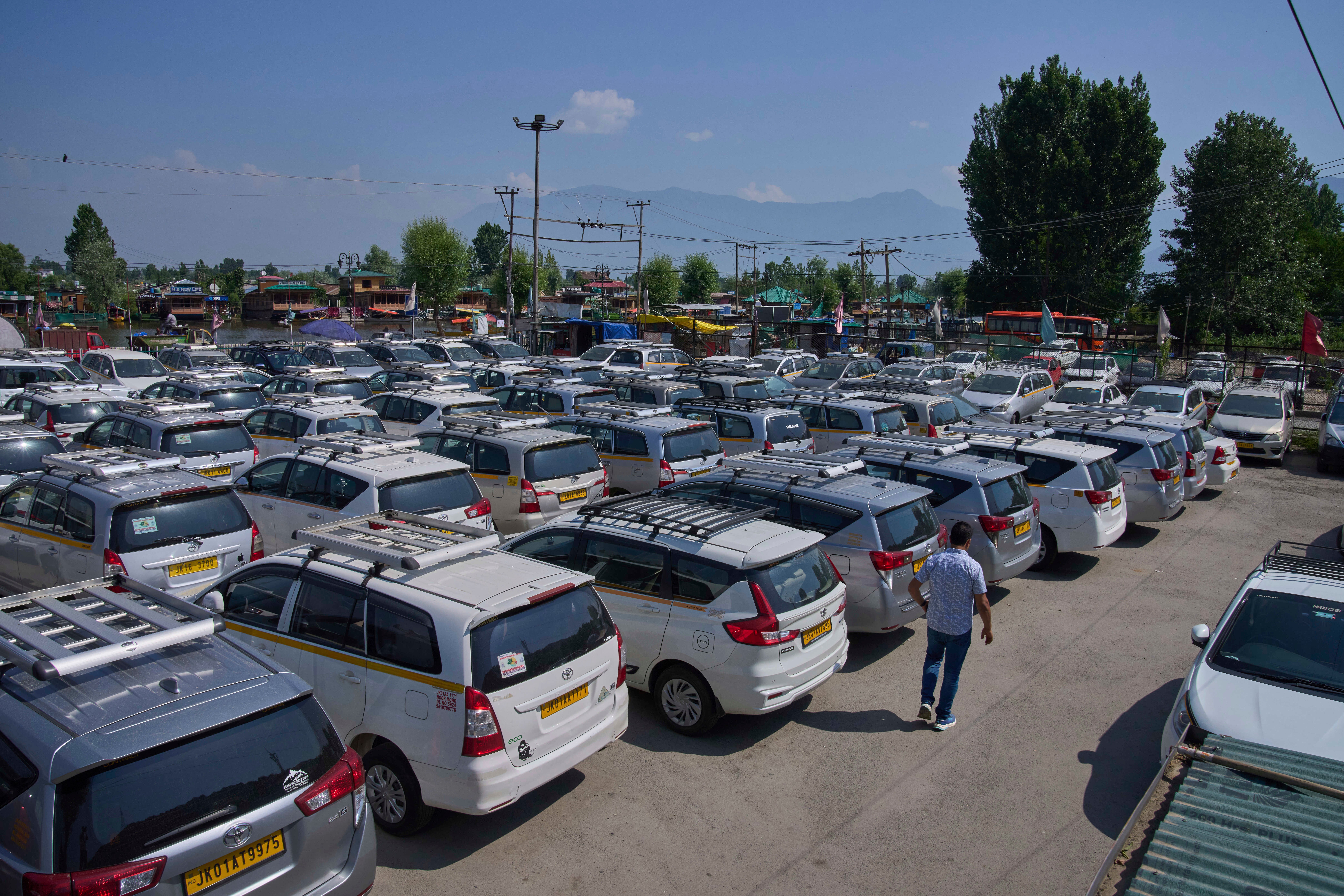 A Kashmiri taxi driver walks past hundreds of tourist cabs parked idle in Srinagar, Indian controlled Kashmir, India on Tuesday, May 20