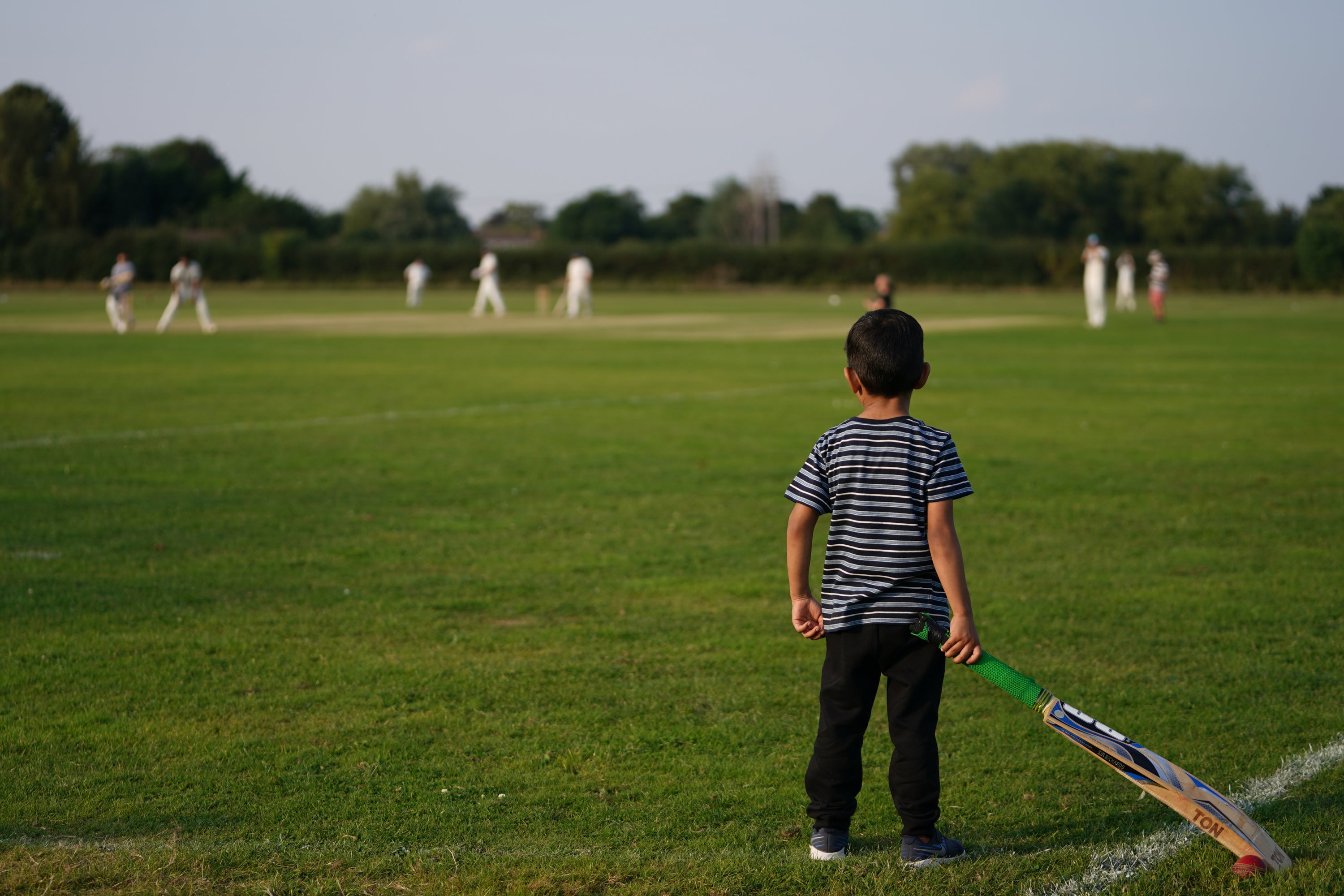 A recently arrived Afghan youngster watches on from the boundary during a cricket match with members of Newport Pagnell Town Cricket Club in Buckinghamshire, organised by the club as a gesture to welcome them to the UK