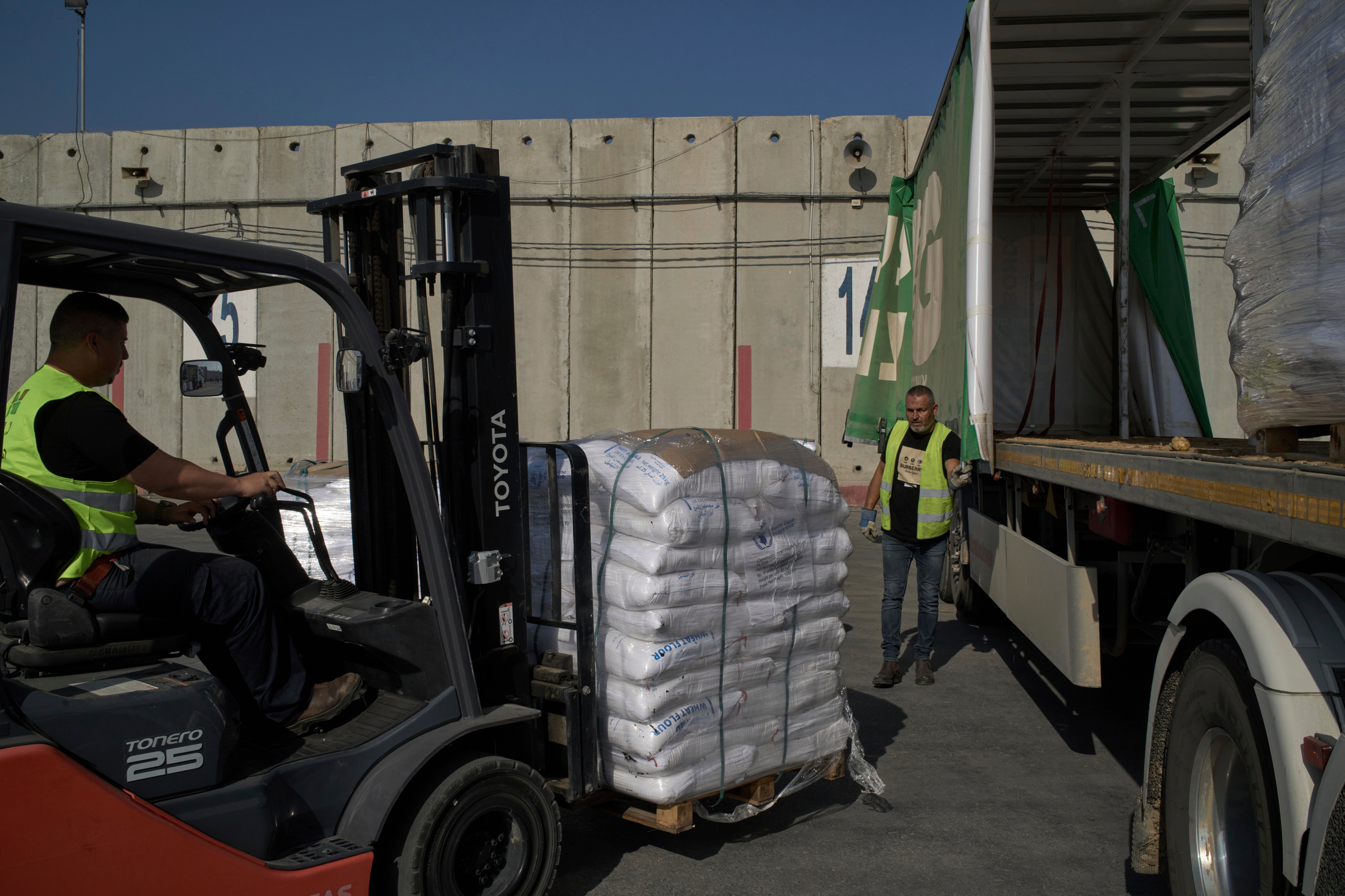 Workers unload cargo from a truck carrying humanitarian aid for the Gaza Strip at the offload area of the Kerem Shalom border crossing between Israel and Gaza