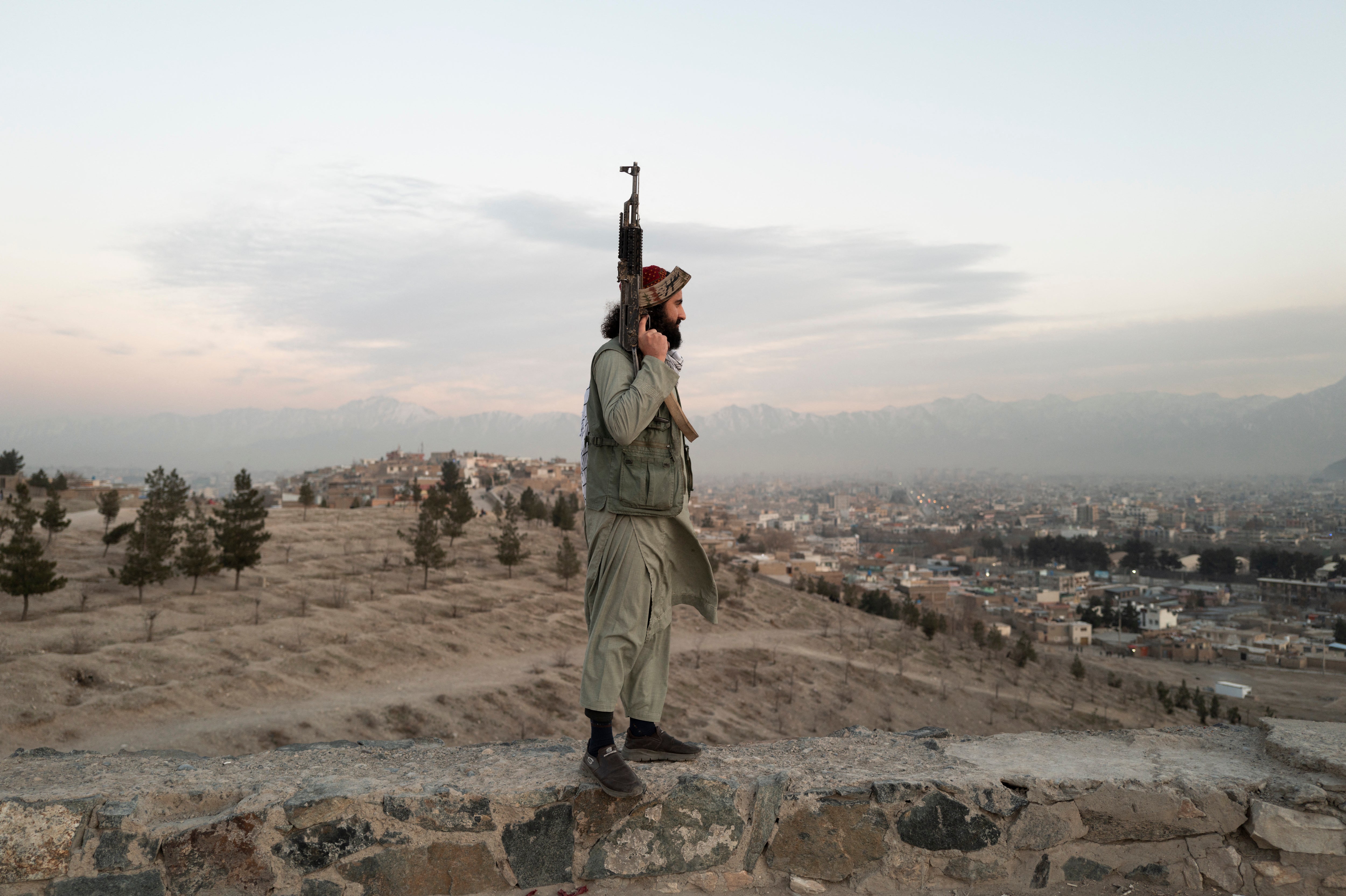High above Kabul, a Taliban soldier armed with a Kalashnikov looks down on the city